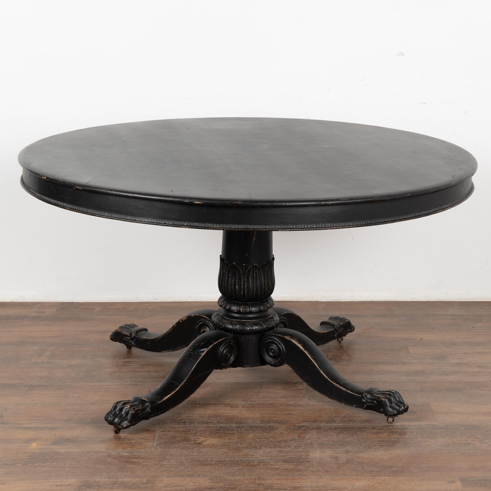This round pine pedestal table has a carved skirt, turned pedestal base resting on four carved legs with lion's paw feet and casters.
Restored, later professionally painted in black and lightly distressed to fit the age and grace of this striking