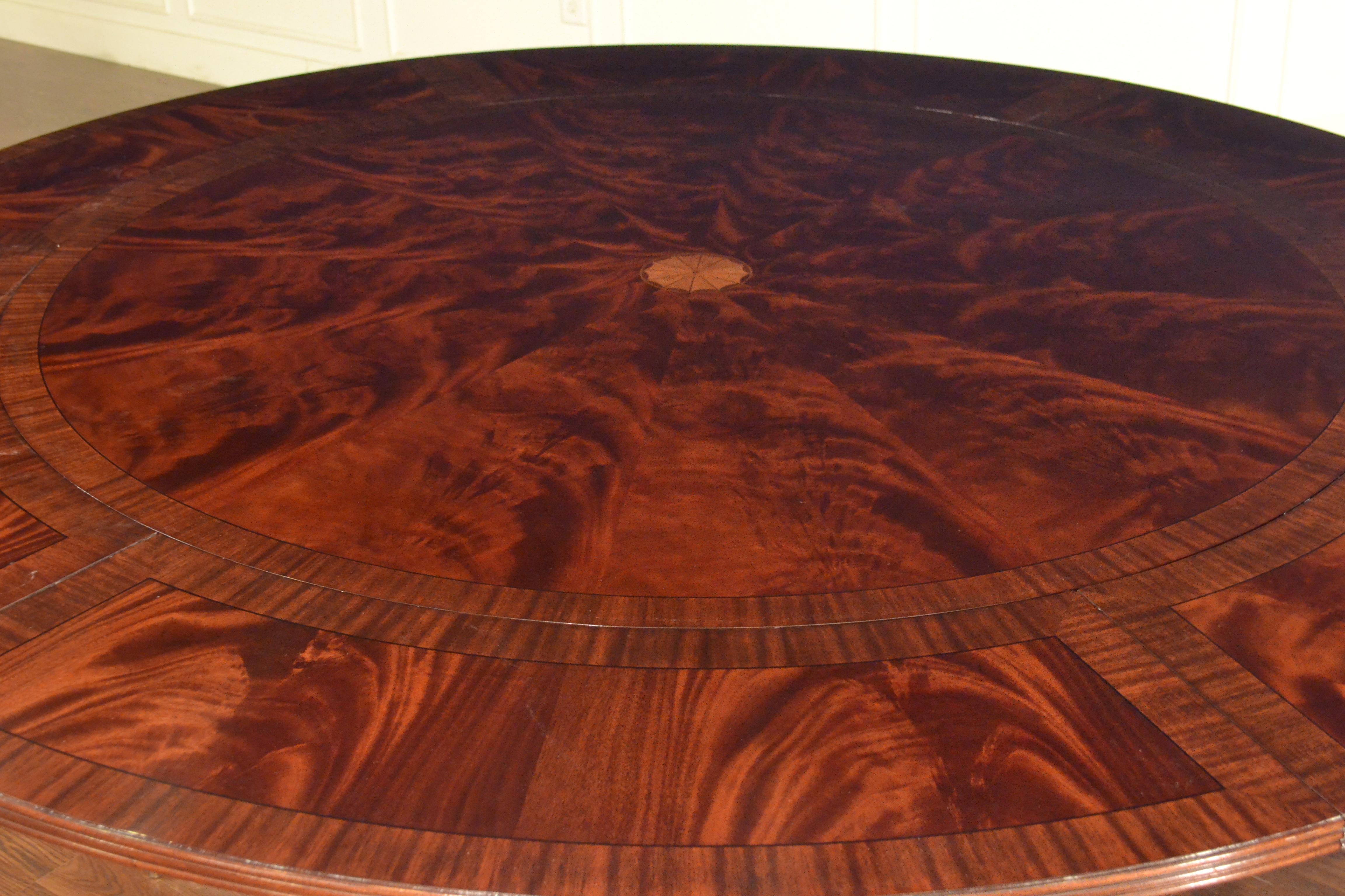 This is made-to-order round traditional mahogany dining table made by Leighton Hall. It features field of radial cut West African swirly crotch mahogany and borders of straight grain mahogany. There are inlays of ebony and white maple which separate
