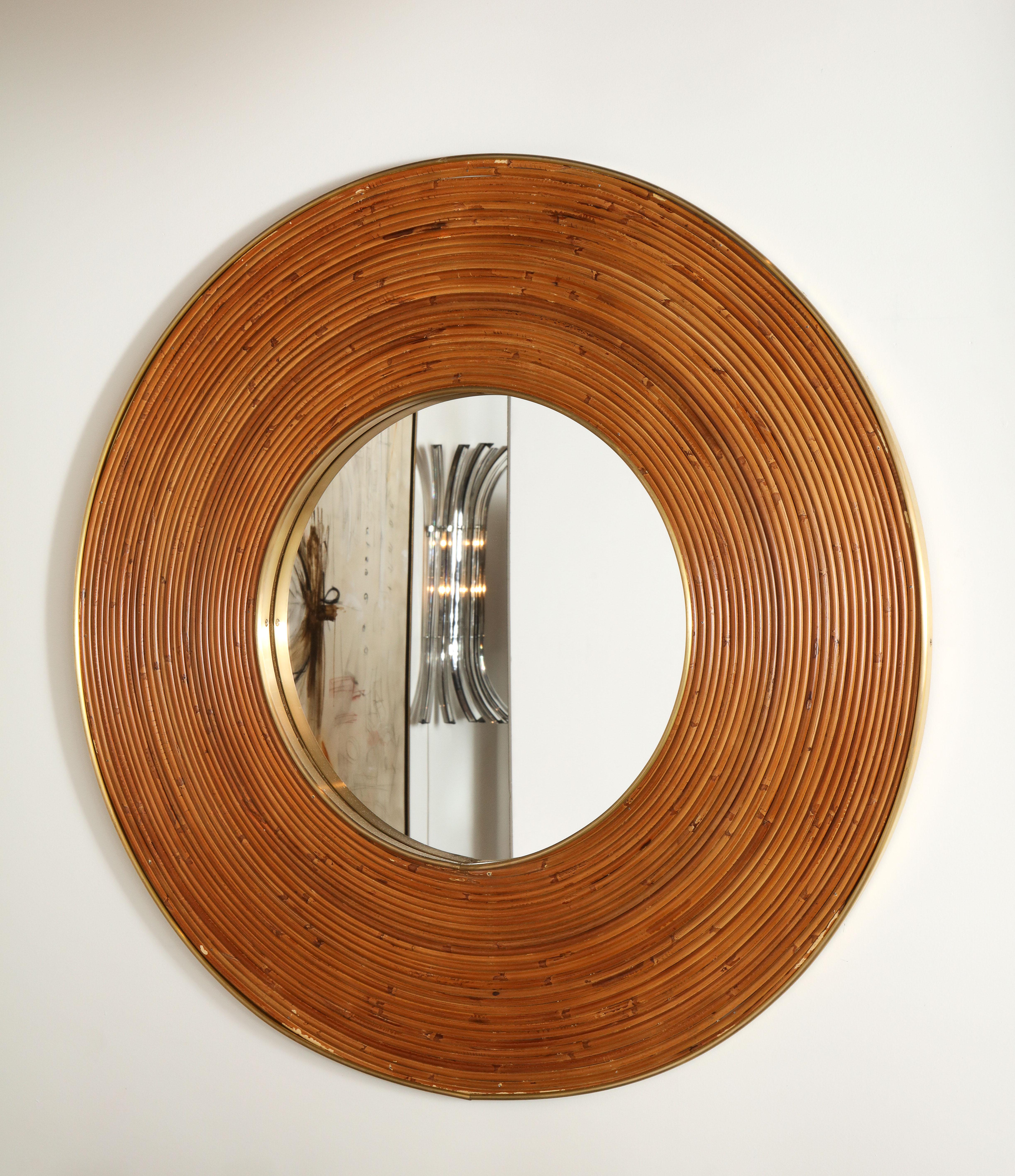 Large round mirror consisting of weaved natural reed and polished brass around the interior and exterior outermost perimeter. Excellent condition. Italy, circa 1970s. In perfect vintage condition. There is no damage to the reed. Polished brass