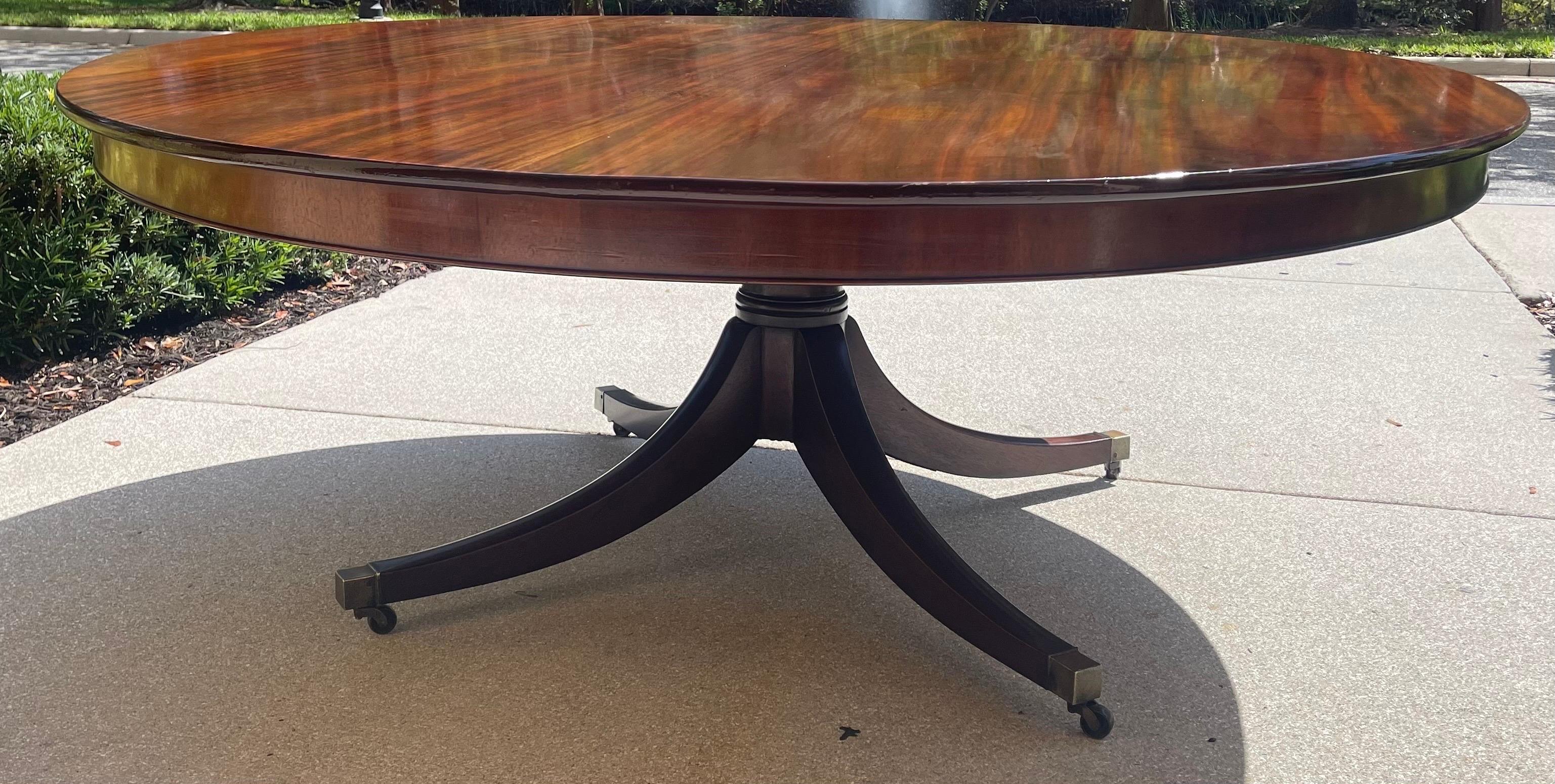 A fine 76” diameter Regency style solid mahogany dining table/ center table,
custom made in the US using the finest Materials in the early 1990s. 
The pedestal consists of four sabre legs ending in solid brass square castors on wheels. 
This