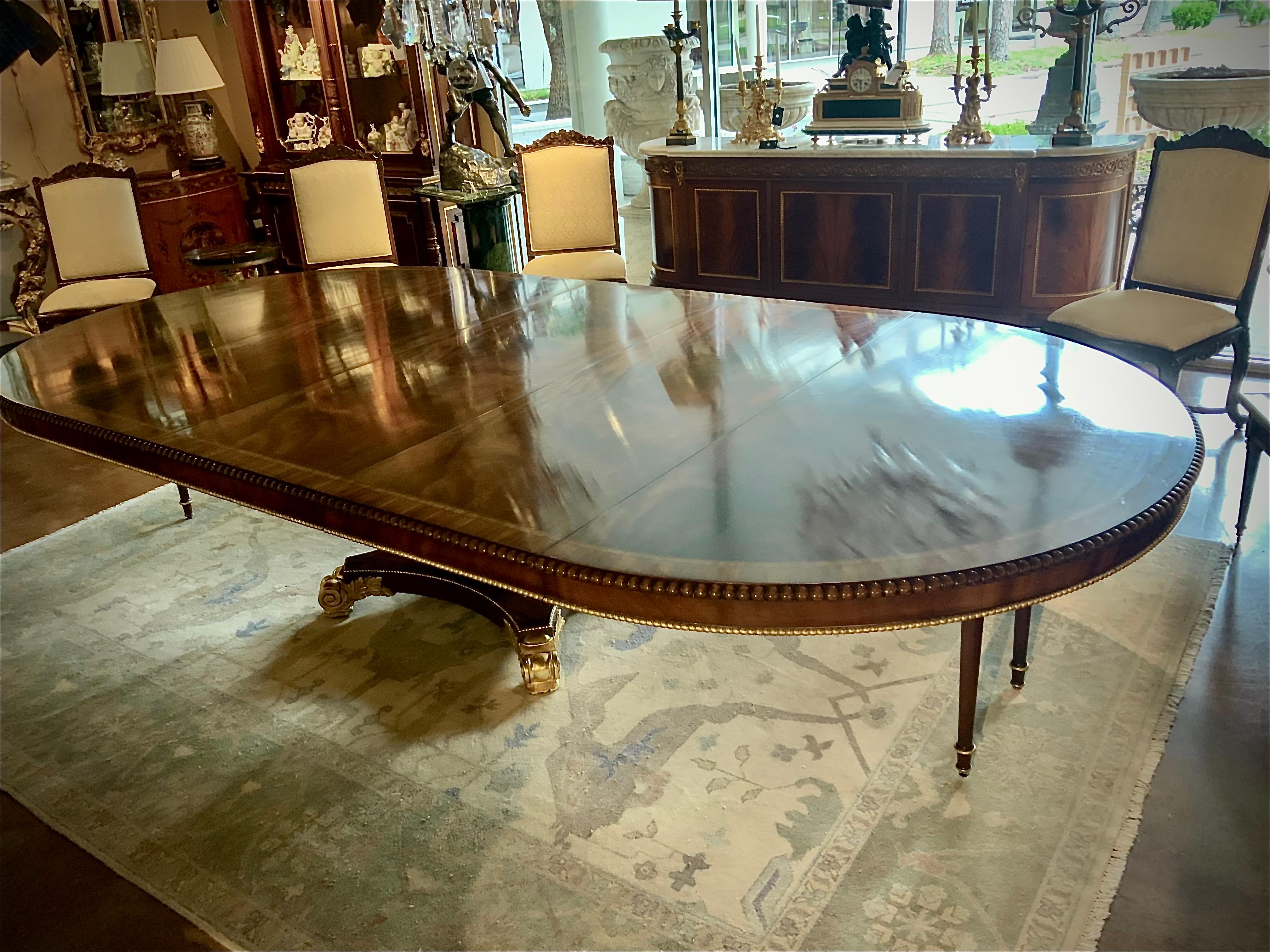 This English Regency Style (20 th Century) circular  mahogany 
Pedestal table extends to make a very large oval table.
It has three 24” leaves; it has a handsome pedestal with
Gilt feet. It has two additional drop down legs for extra
Support when