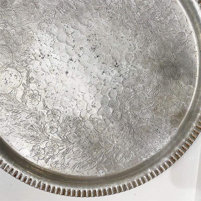 Add a touch of bohemian to your next party. This aluminum tray is the perfect way to service drinks, display fruit or to place crudités. Round with a scalloped pie crust edge, the center features engraved designs of fruit and flowers. Sourced from