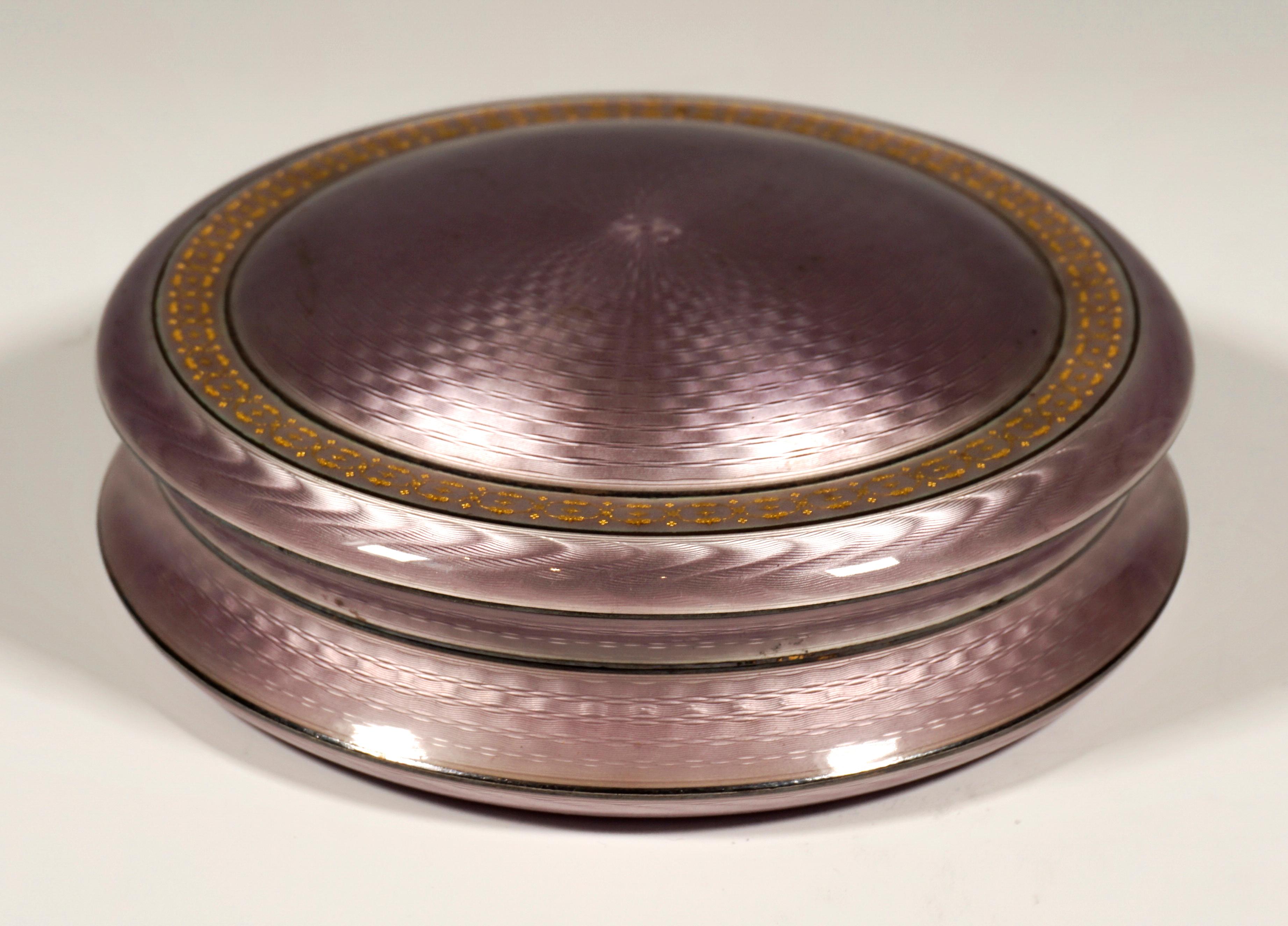 Exquisite enamel box from the period around 1900.
Large silver box, round shape, completely engine-turned and enamelled in lilac, slightly arched lid with wicker-like, interwoven line decoration and circumferential border with gold decoration,