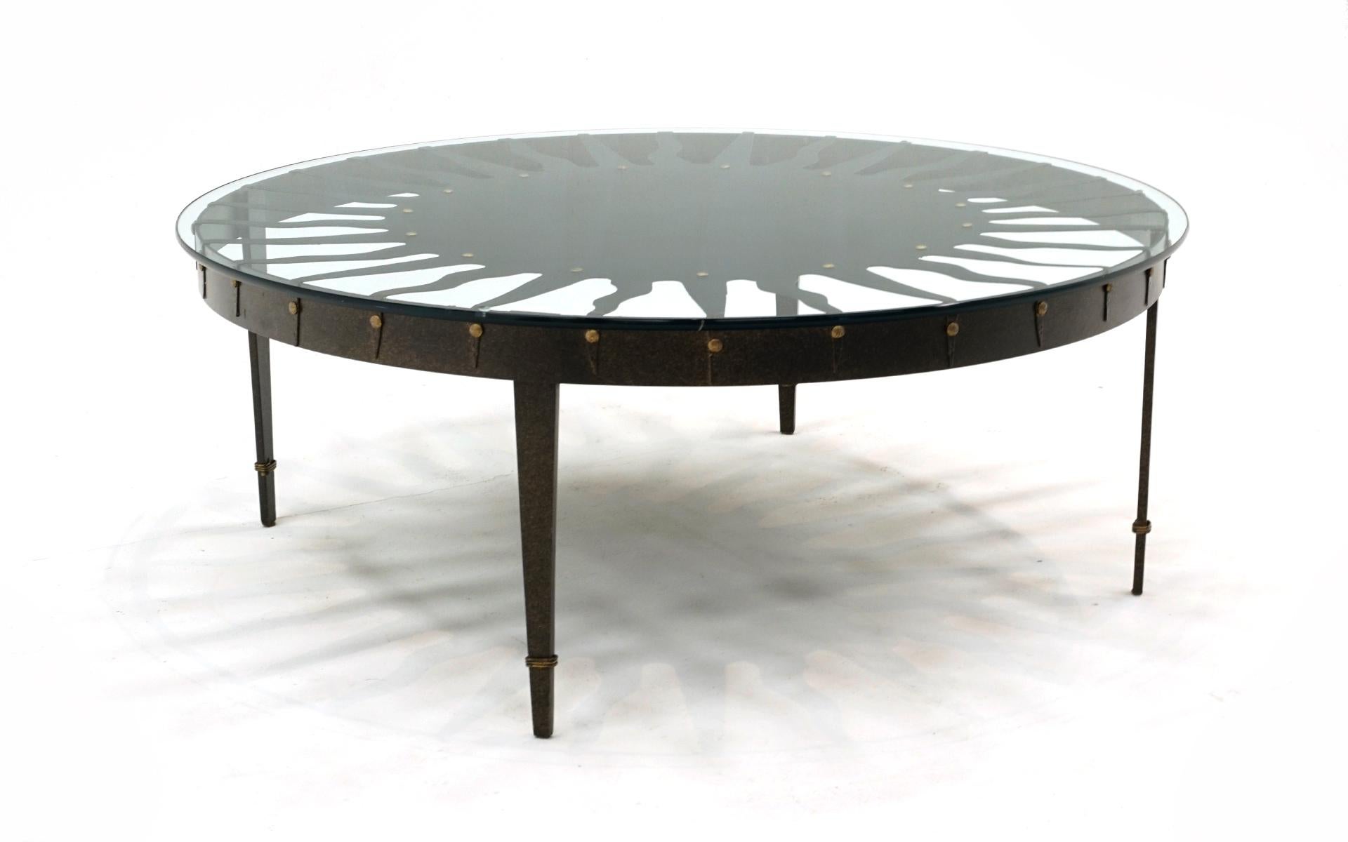 Iron and glass coffee table with sunburst design.  The base is black with subtle gold accents and in very good condition with few signs of use.  The original 3/8' glass top with rounded edges has not chips or significant scratches.  This piece is