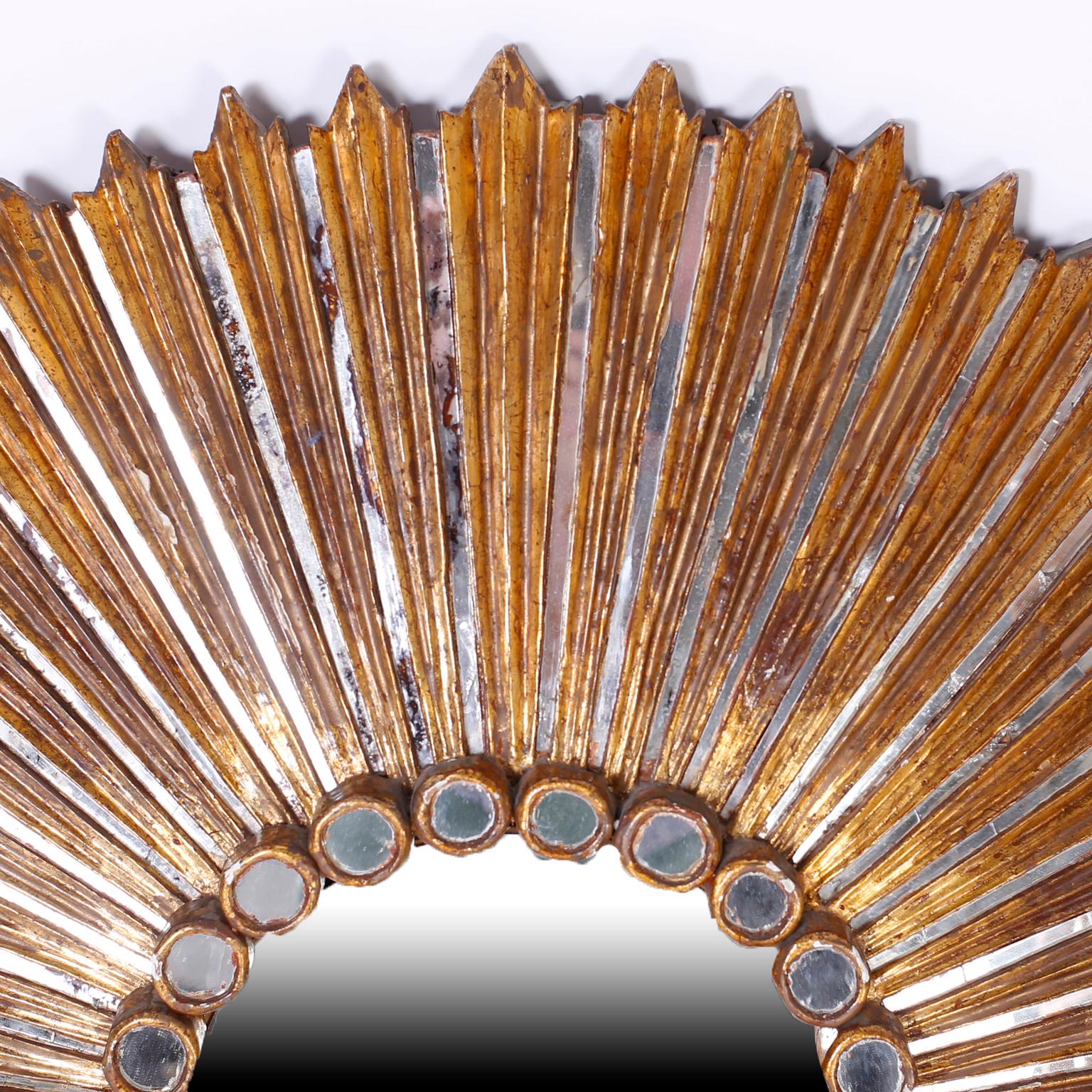 A beautiful large round carved and gilt sunburst mirror with great surface. Small mirrored panels alternate with giltwood rays, around a central mirror. The mirrored panels showing signs of age and wear. A great decorative statement.

  
