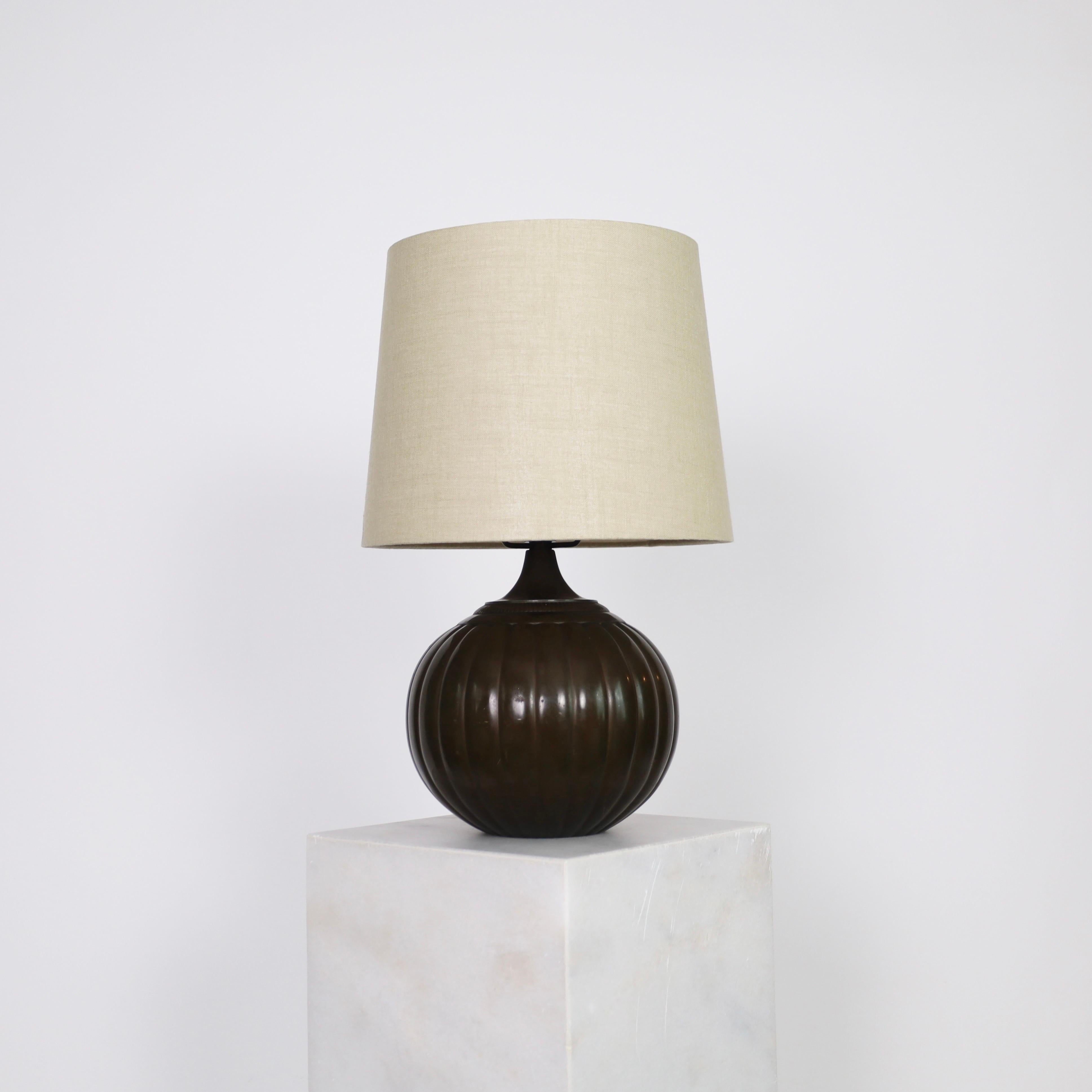 Round Table Lamp designed by Just Andersen in 1934. An elegant and rare piece for an exquisite home.  

* A round metal lamp with vertical lines and a beige fabric shade
* Designer: Just Andersen
* Model: 1632 (stamped ‘Just 1632’)
* Year: 1934
*