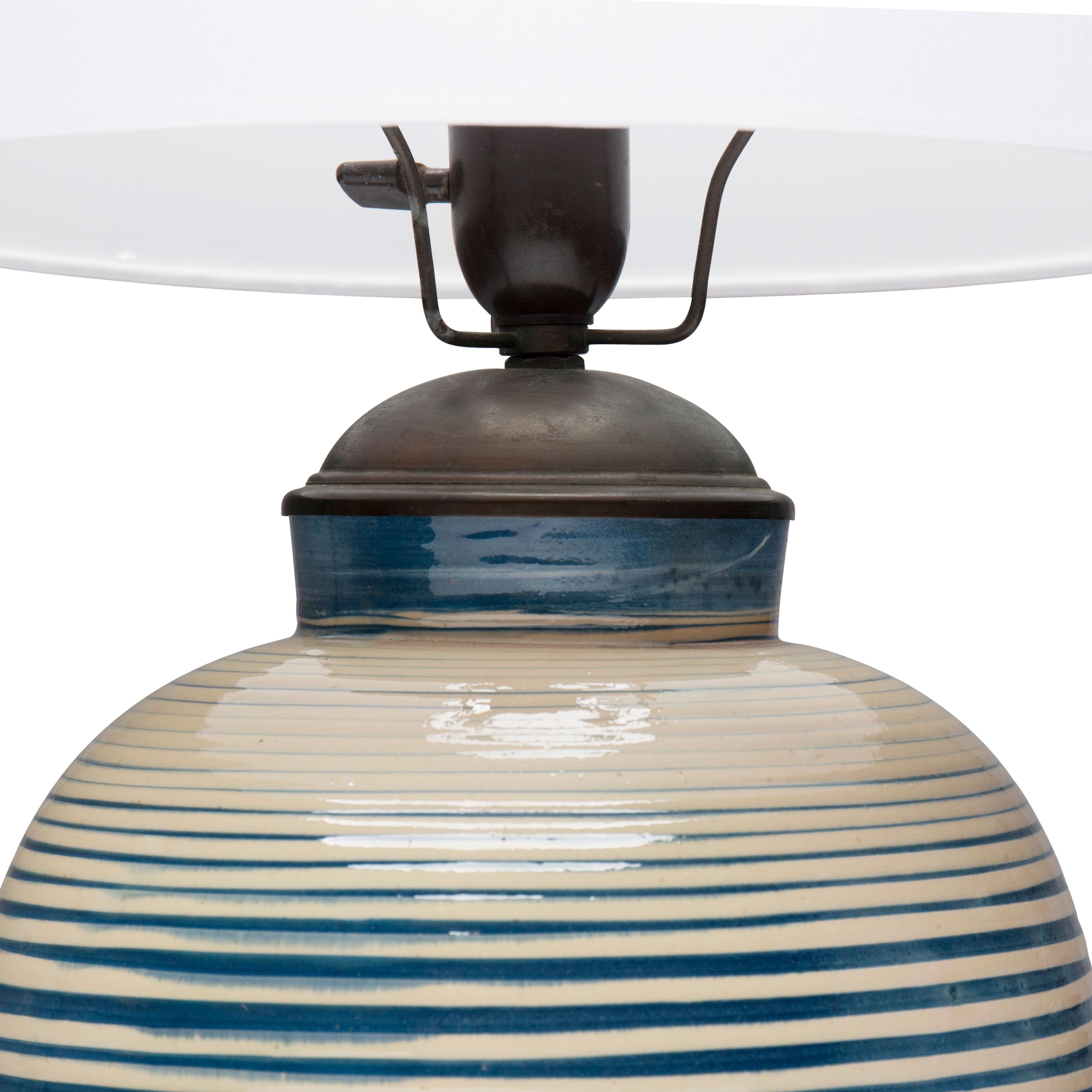 This large table lamp has horizontal blue stripes on a creamy background.

The lamp was executed by Herman A. Kähler, Denmark, ca. in the 1940s.

It has the ‘HAK’ monogram incised.
