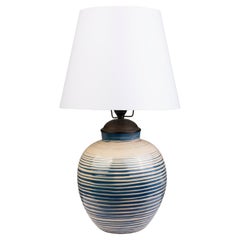 Gran lámpara de mesa redonda con rayas horizontales azules sobre fondo crema