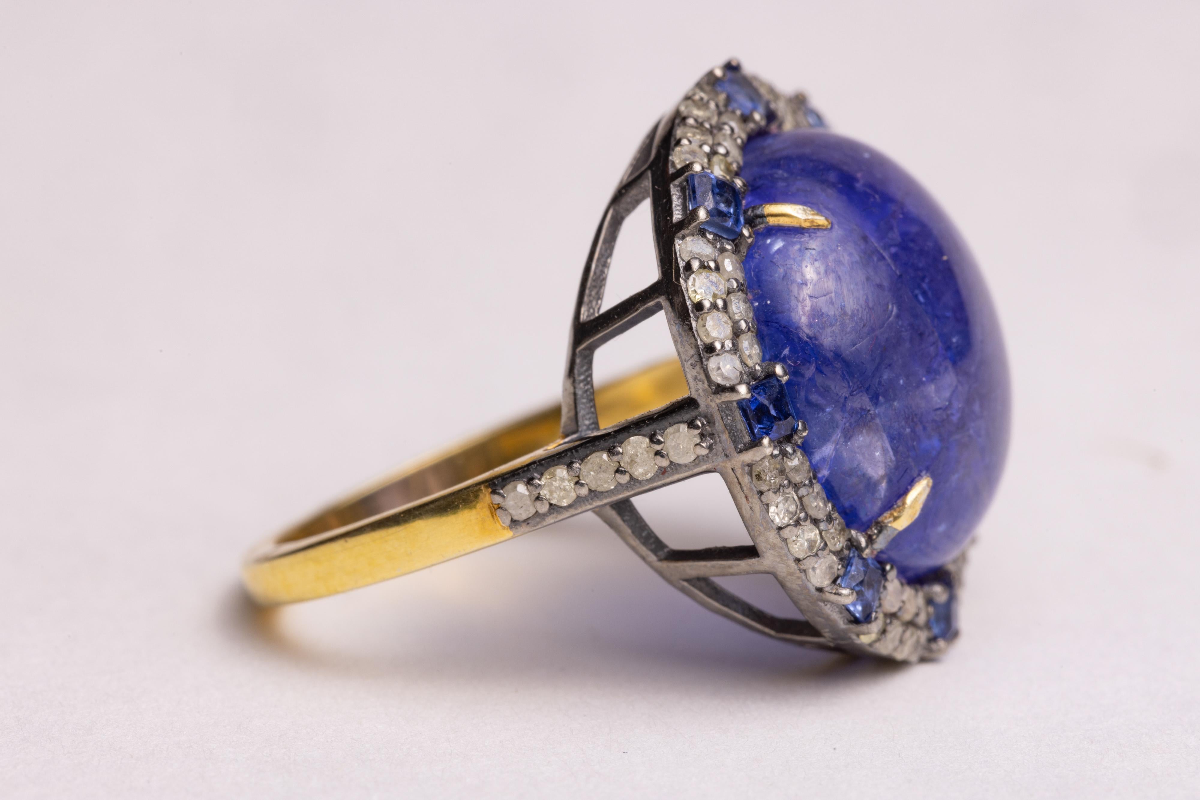 A large, stunning round cabochon Tanzanite dome cocktail ring.  Surrounded by two rows of round, brilliant cut diamonds with 8 faceted, square-cut sapphires in between.  Set in sterling silver and 18K gold vermeil.  ring size is 7.25.  Carat weight