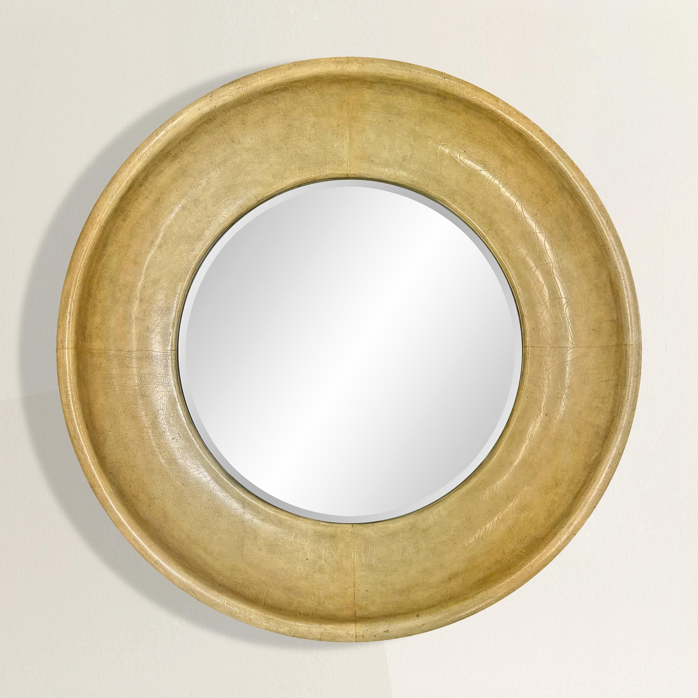 This late 20th-century American round mirror combines sleek modernism with timeless materials, making it a versatile centerpiece for any interior. The deep-profile frame is wrapped in luxurious goat skin, or vellum, its subtle texture adding depth