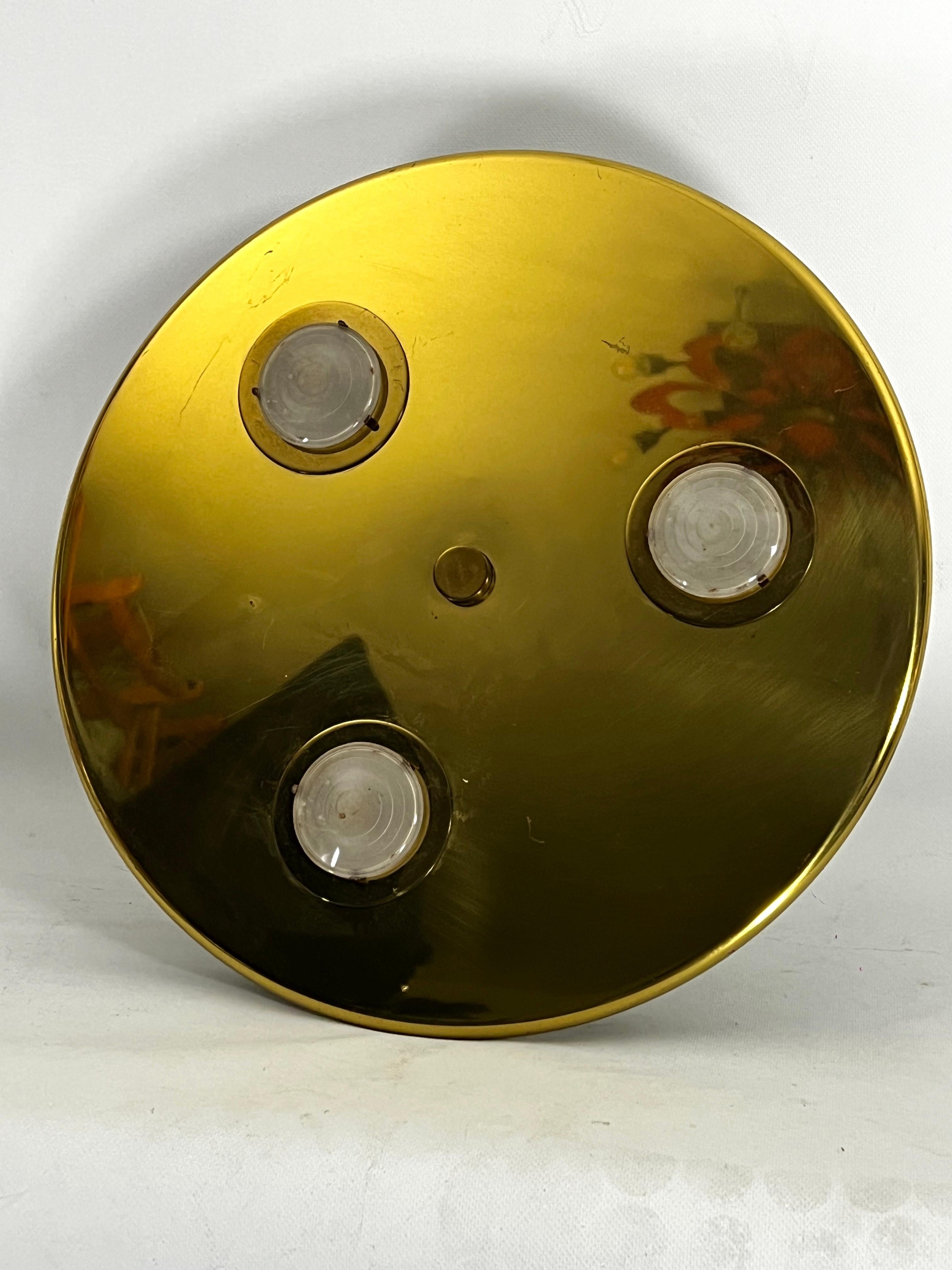 This Gilded brass round ceiling or wall lamp with three glasses has been produced in Italy during the 70s.
Good vintage condition with normal trace of age and use. No cracks or chips. Slight scratches and some dots on the brass. Full working with EU