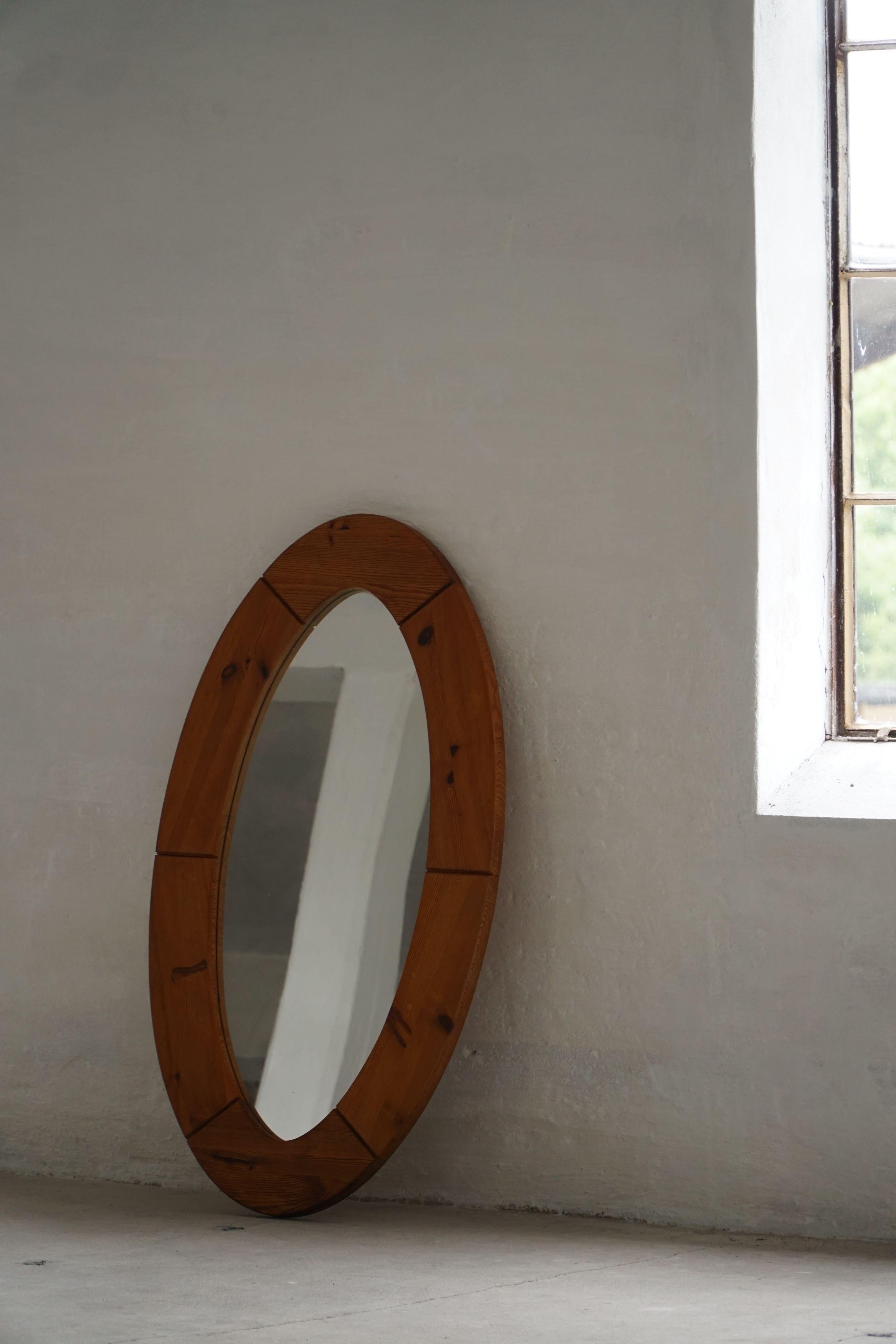 This sculptural wall mirror was crafted in Sweden during the 1960s by Glasmäster Markaryd and features a broad, rounded frame in solid pine. The wood has aged beautifully, with a warm tone and visible grain structure that highlights natural knots