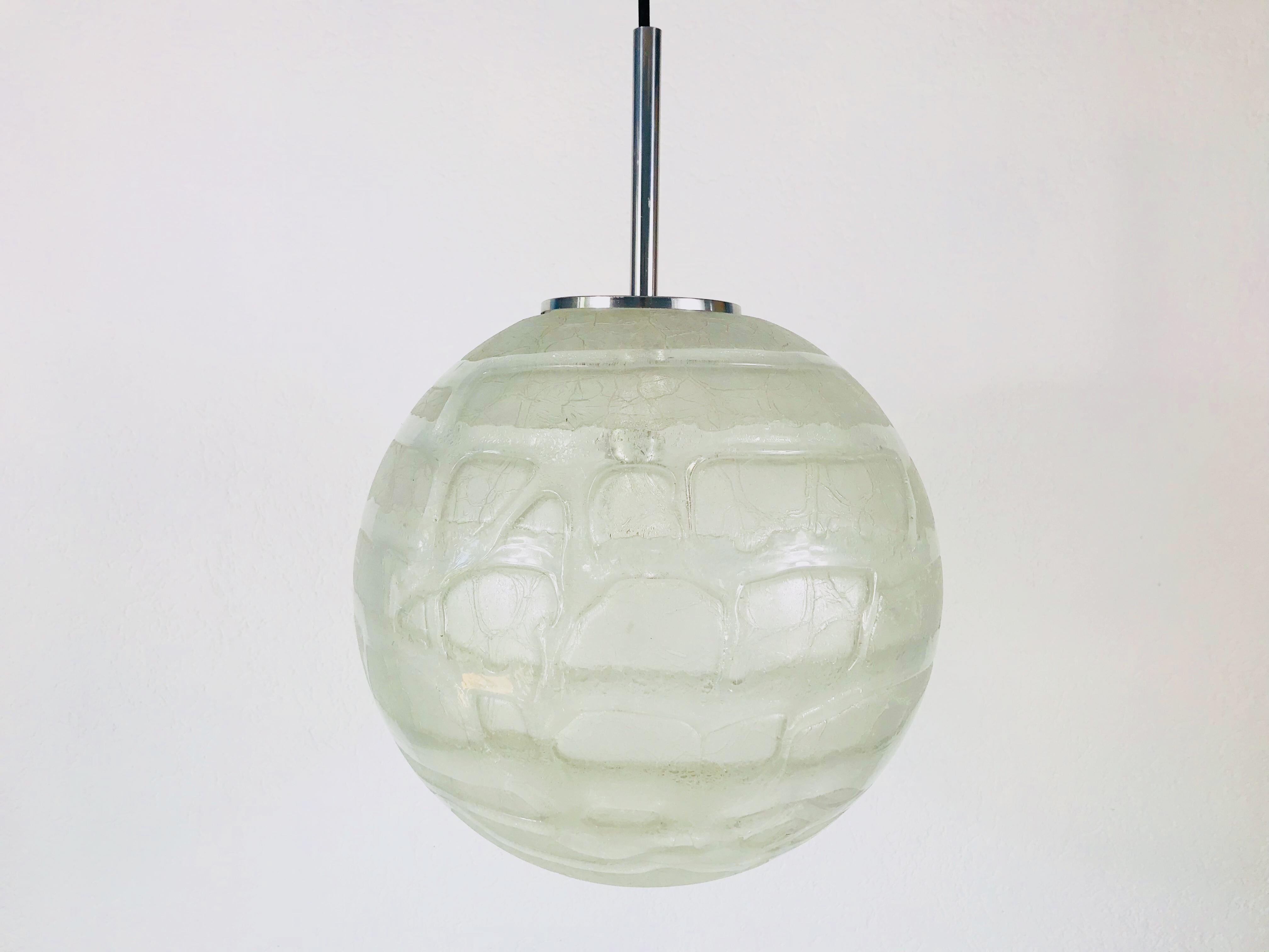 Eine schöne Hängelampe aus Glas, hergestellt in Deutschland in den 1970er Jahren. Die Leuchte ist aus Muranoglas gefertigt. Es hat eine erstaunlich transparente Farbe und ist sehr solide. Die Oberseite der Lampe ist aus verchromtem Aluminium.

Die