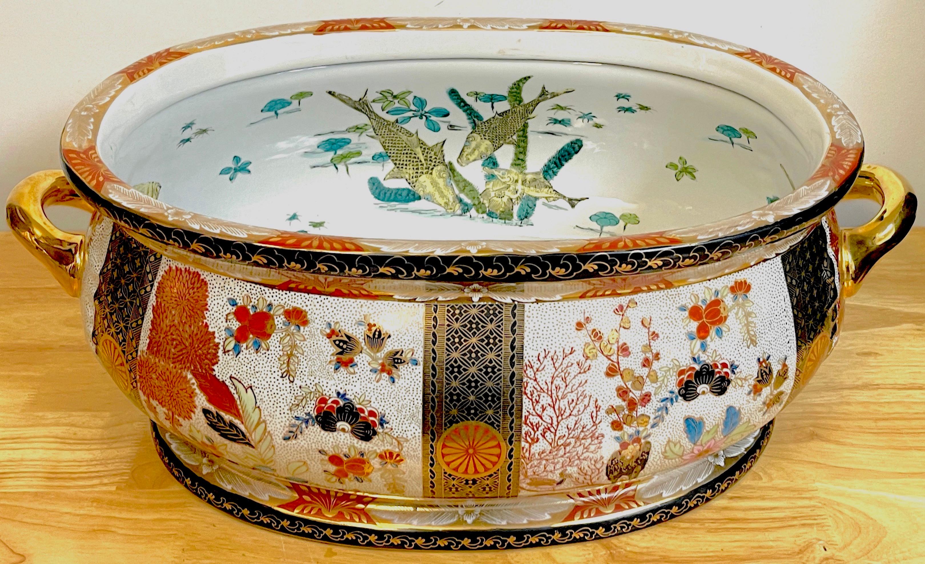 Large Royal Crown Derby style 'Imari' pattern centerpiece, profusely hand-painted decorated with rich, vibrant colors and gilt, unusual seaweed and floral patterns. The interior with painted with fish motifs. With twin gilt handles. Unmarked.
The