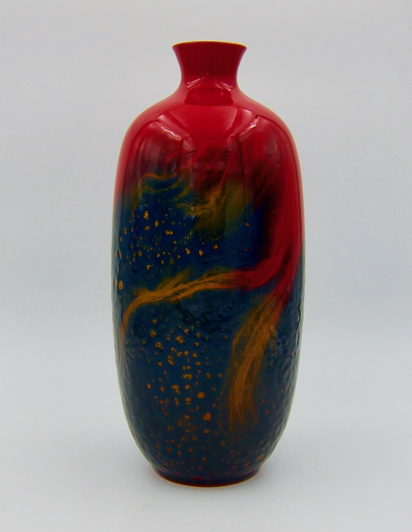 A large Royal Doulton Flambé vase from the Art Deco period, dating circa 1930. The rim and shoulders of the English art pottery vessel are decorated with a bold and glossy glaze of deep red over a textured blue body accented with fiery tendrils of