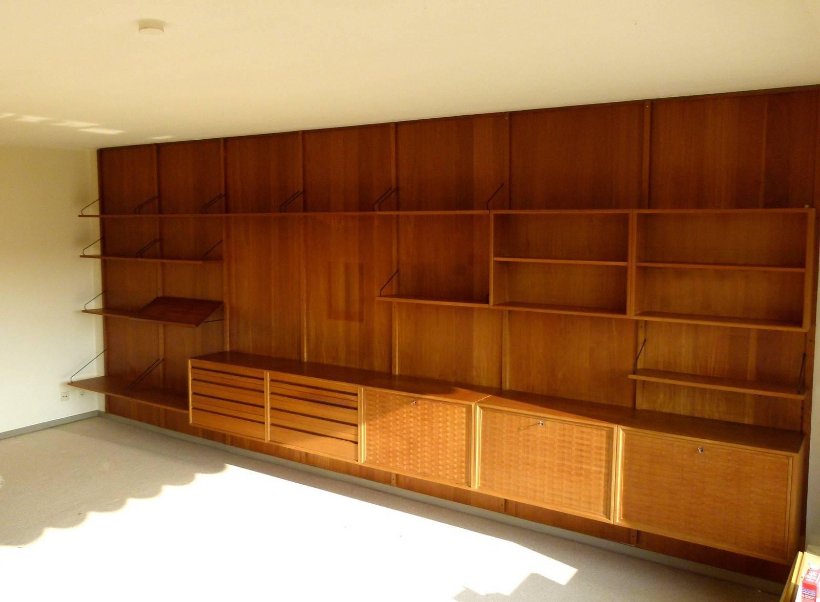 This large Royal System shelving unit was designed by Poul Cadovius for Cado in 1958 or 1959. It features surfaces in teak veneer and mounts of black coated metal. The back walls are coverings, which are fastened with the strips. Please note that