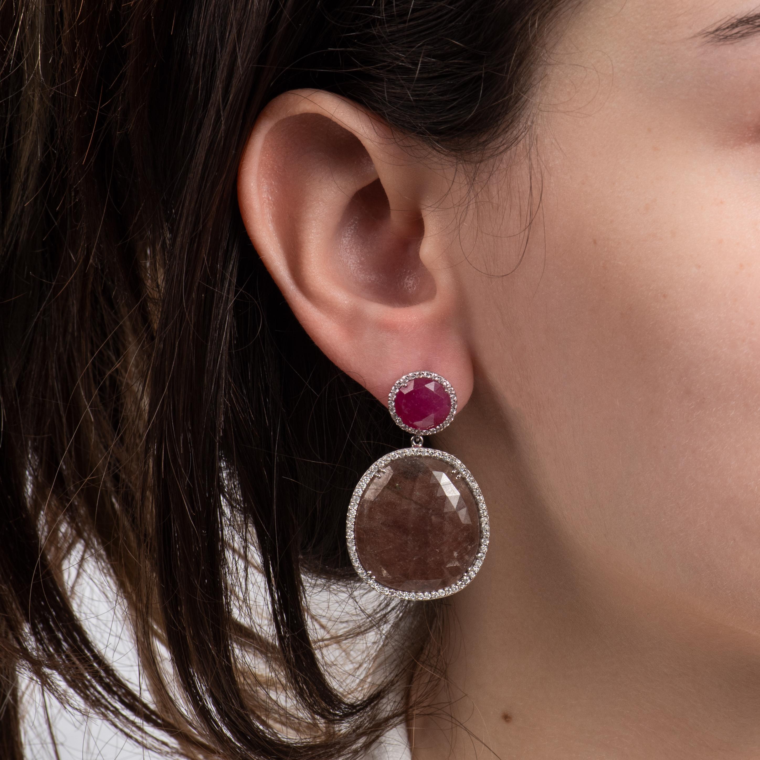 These unique earrings feature some incredible, faceted sapphire and ruby slices, surrounded by round diamond halos. The bottom sapphires are approximately 22.67mm x 24.66mm, and the top rubies are approximately 9.91mm x 9.93mm. The diamond halos are