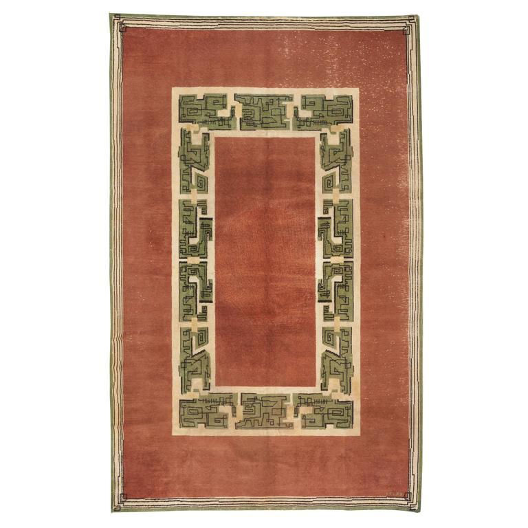 Woollen rectangular rug colored with green, black and ivory geometrical forms on an ochre background.