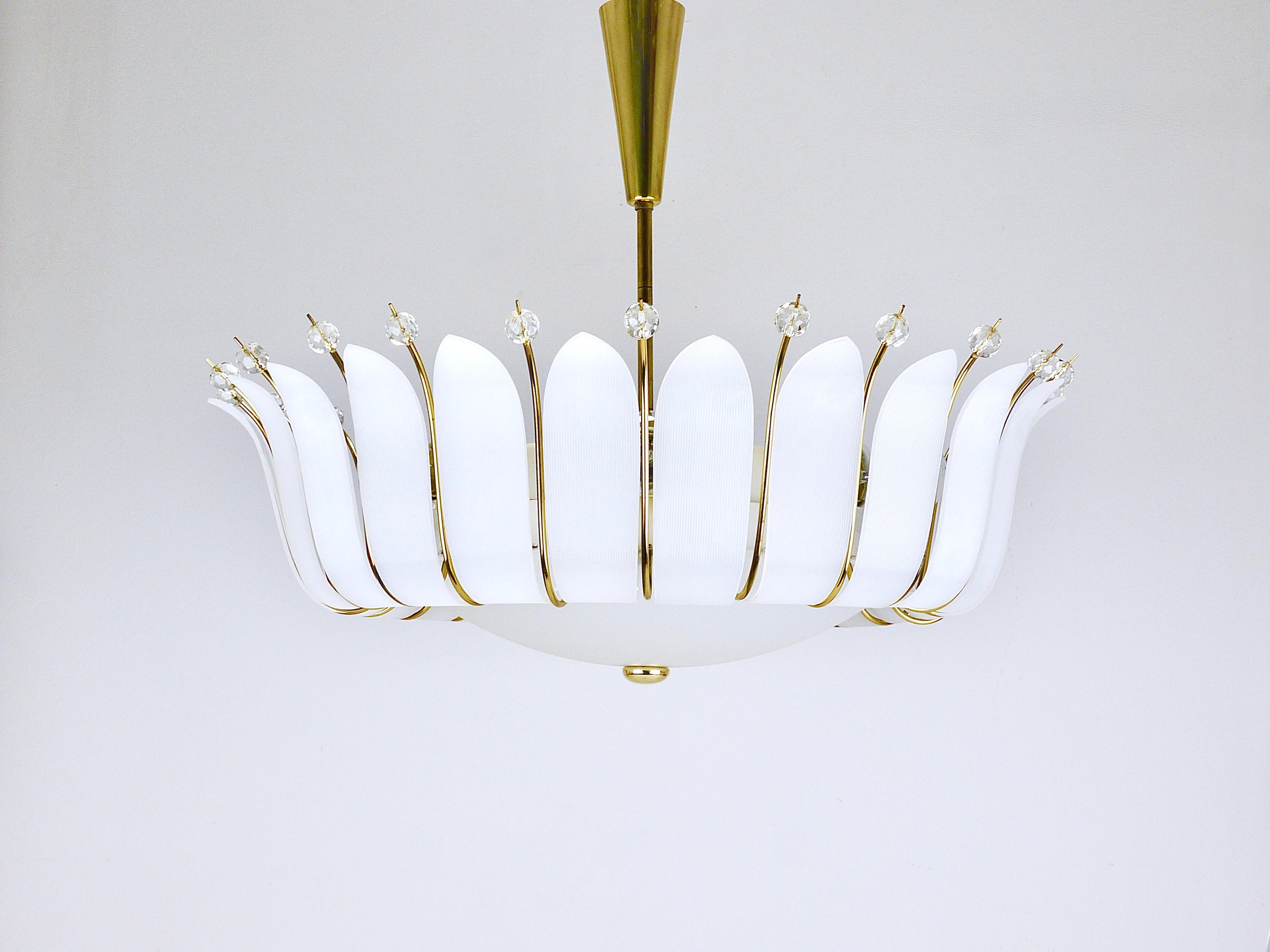 Un bellissimo e grande lampadario modernista austriaco in ottone, disegnato e prodotto da Rupert Nikoll, Vienna, Austria, negli anni Cinquanta. Questo imponente pezzo, con i suoi 27 pollici di diametro, è caratterizzato da foglie acriliche bianche