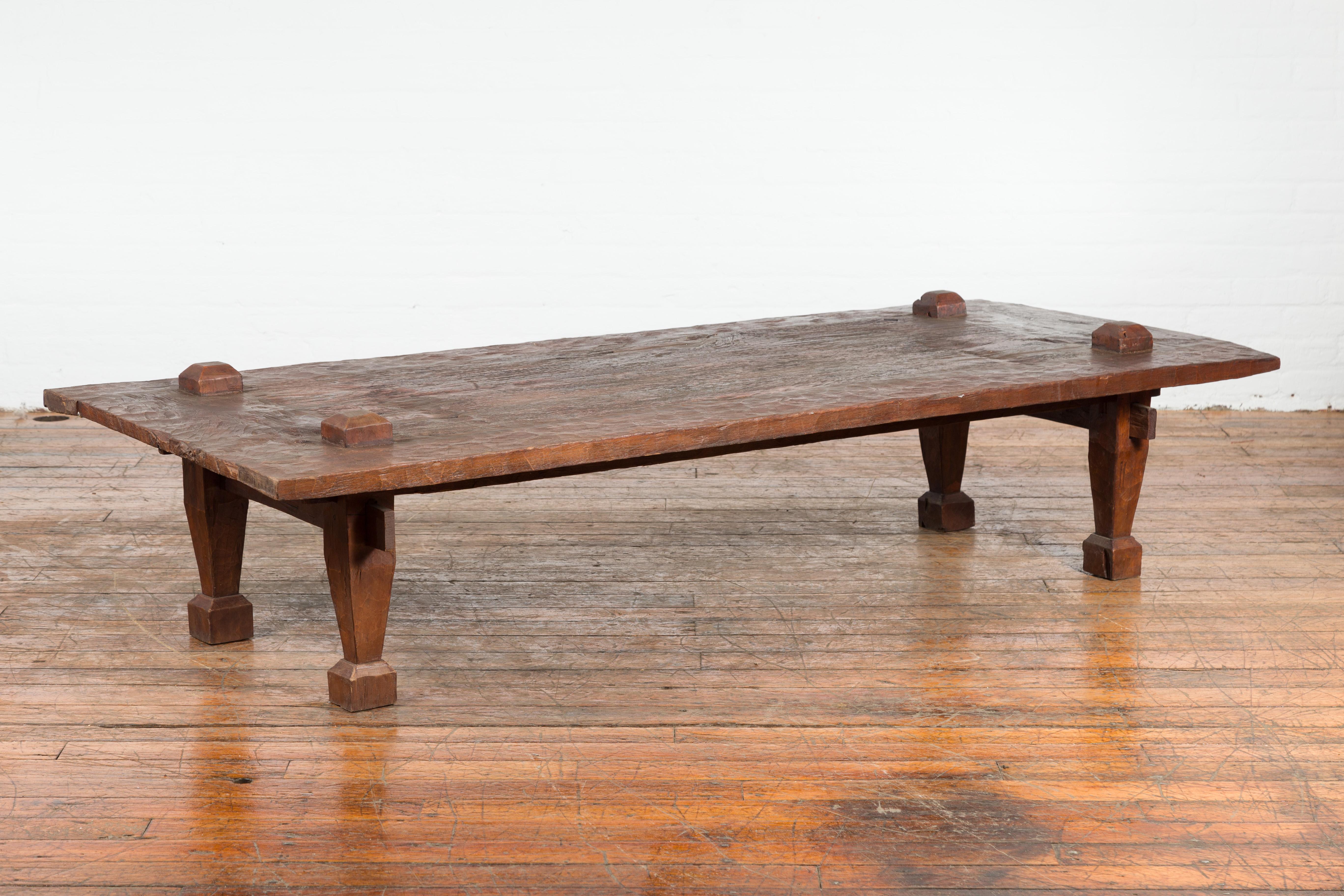 An antique rustic Indonesian coffee table from the 19th century, with raised joints and distressed patina. Created in Indonesia during the 19th century, this large coffee table features a rustic rectangular top with raised joints, sitting above four