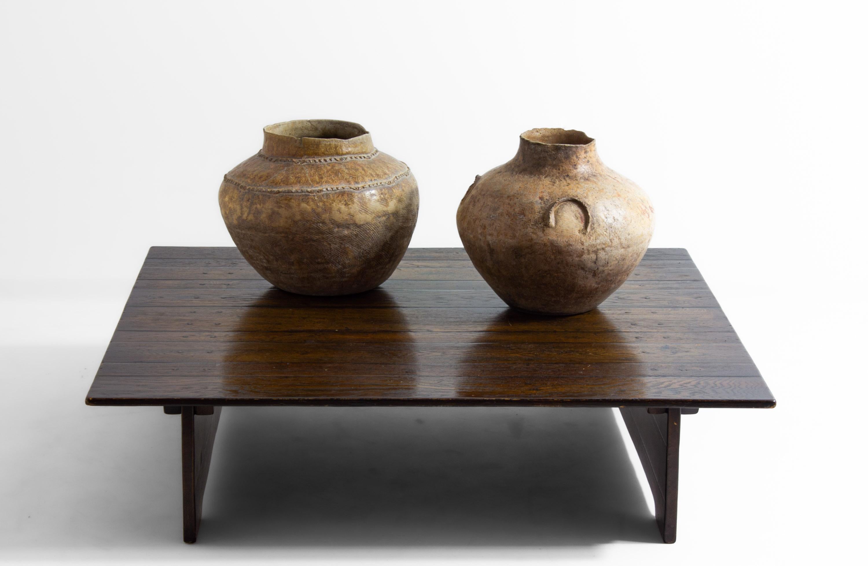 This large square Brutalist coffee table from the 1980s is made from heavy, rugged wood with a strong grain and dark finish. The design is simple and bold, with wide planks forming the top and solid sides serving as legs. Its square shape, measuring