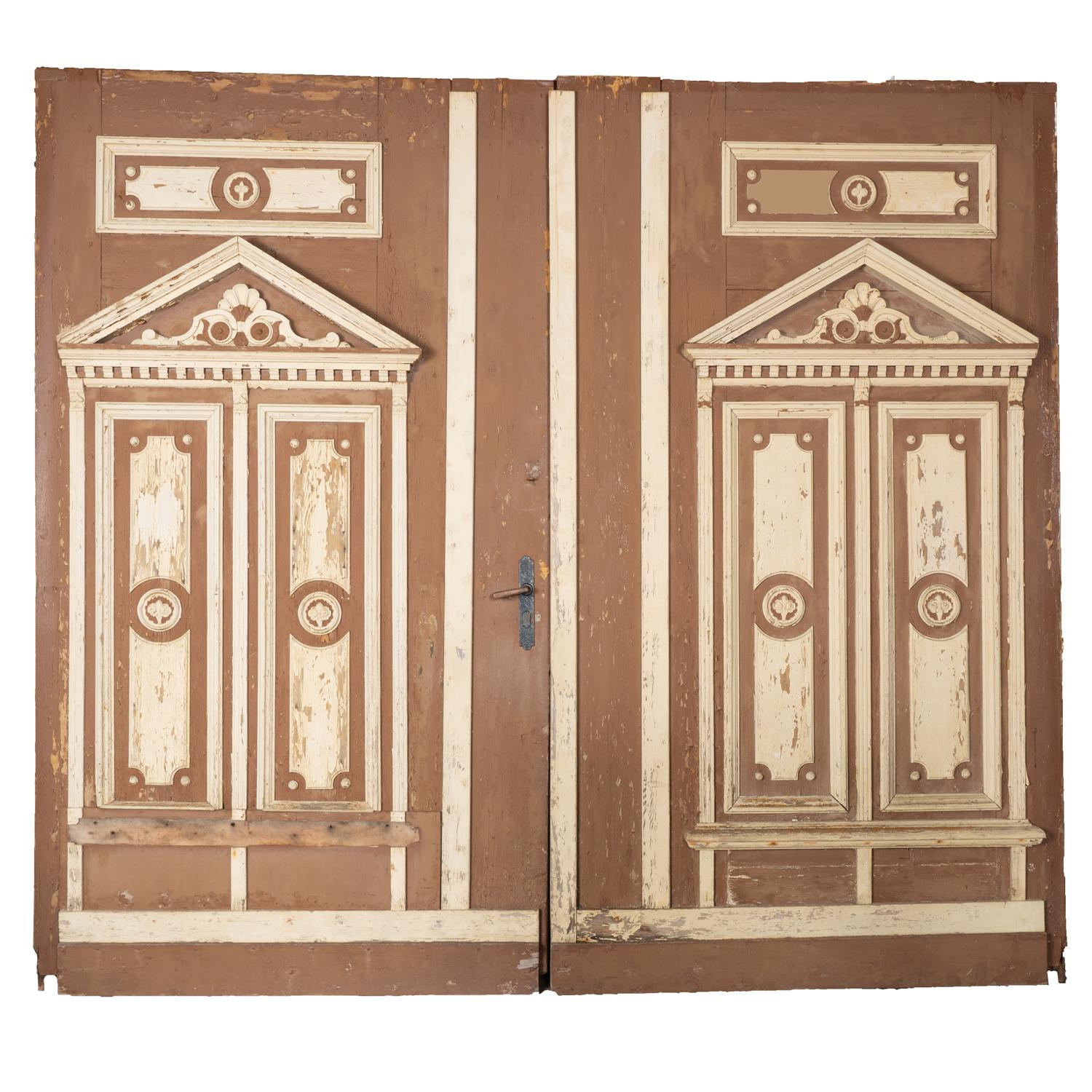 Puertas rústicas extremadamente grandes procedentes de Hungría, de más de 12' de ancho y 11' de alto.
El acabado original pintado de marrón y blanco presenta desconchones, grietas, desperfectos y falta de pintura debido a los años a la intemperie.