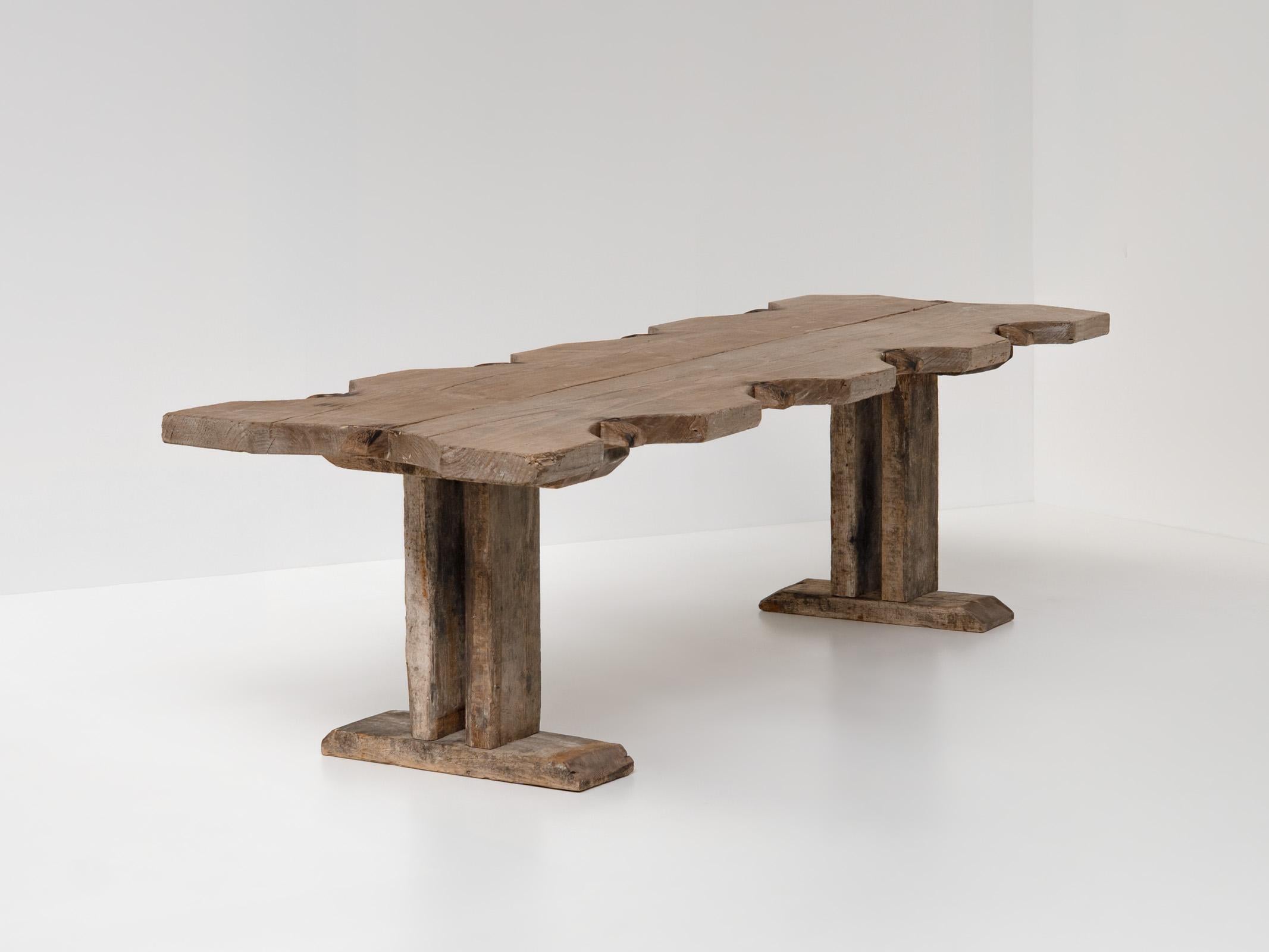 Esta llamativa mesa de comedor vintage de gran tamaño procedente de Francia combina a la perfección el encanto rústico con una sensibilidad moderna. Hecha a mano con madera maciza envejecida, su tablero esculpido de forma única y su base audaz y