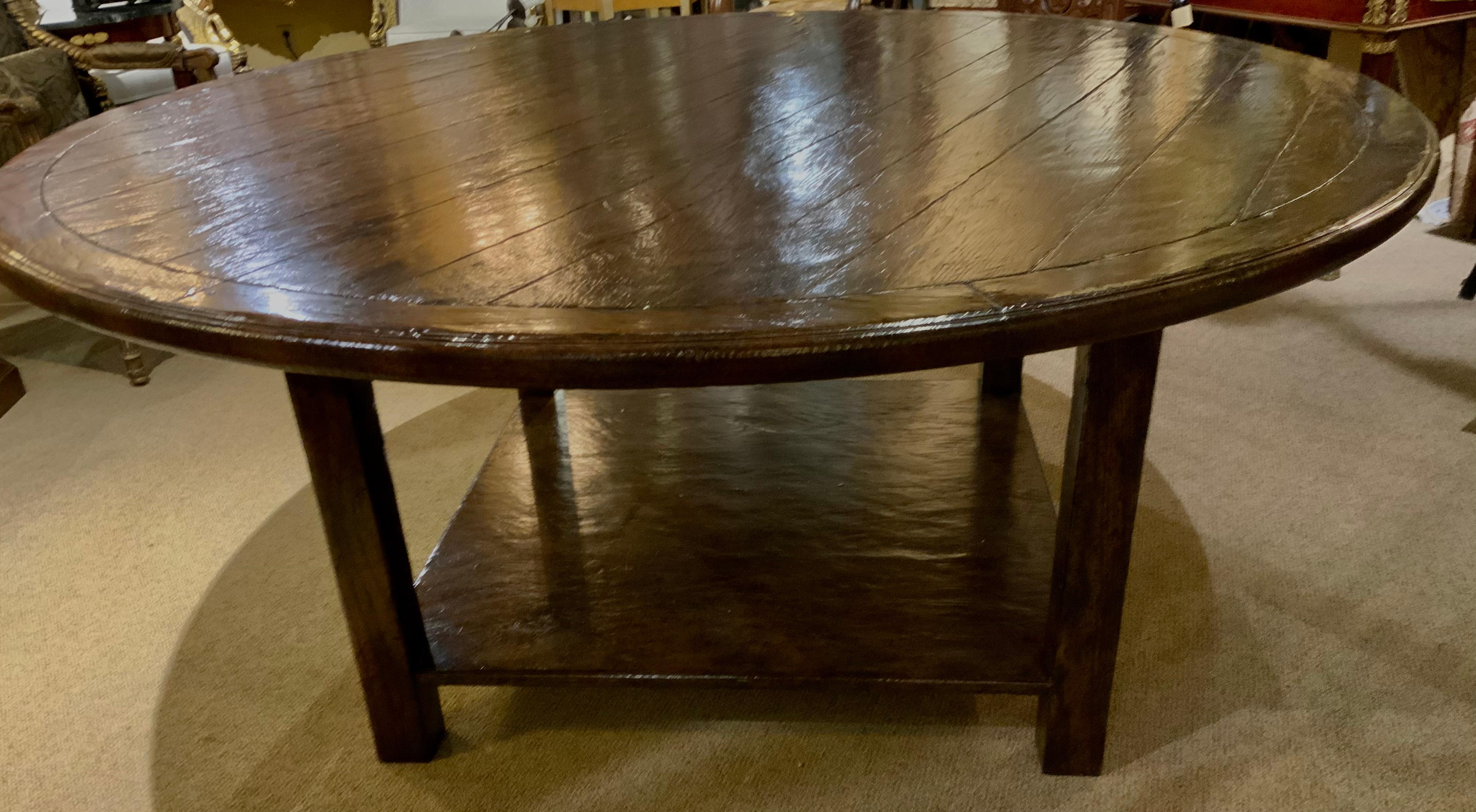 This large round table is well made. It was bench made, the top composed
Of oak boards in varying widths, set in a molded perimeter, raised on a square
Pedestal, the heavy heavy square legs joined by beaded boards and
Pegged construction, and