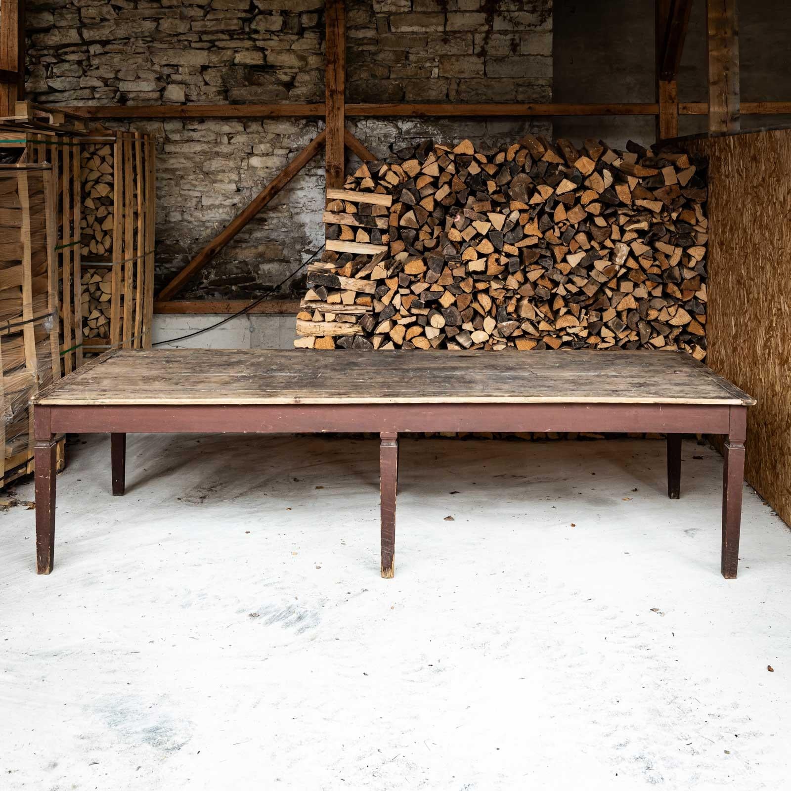 Grande table de salle à manger rustique sur six pieds, avec une légère moulure dans le tiers supérieur et un cadre droit. Le plateau de la table est constitué de poutres en bois continues. La table peut accueillir jusqu'à 12 personnes.