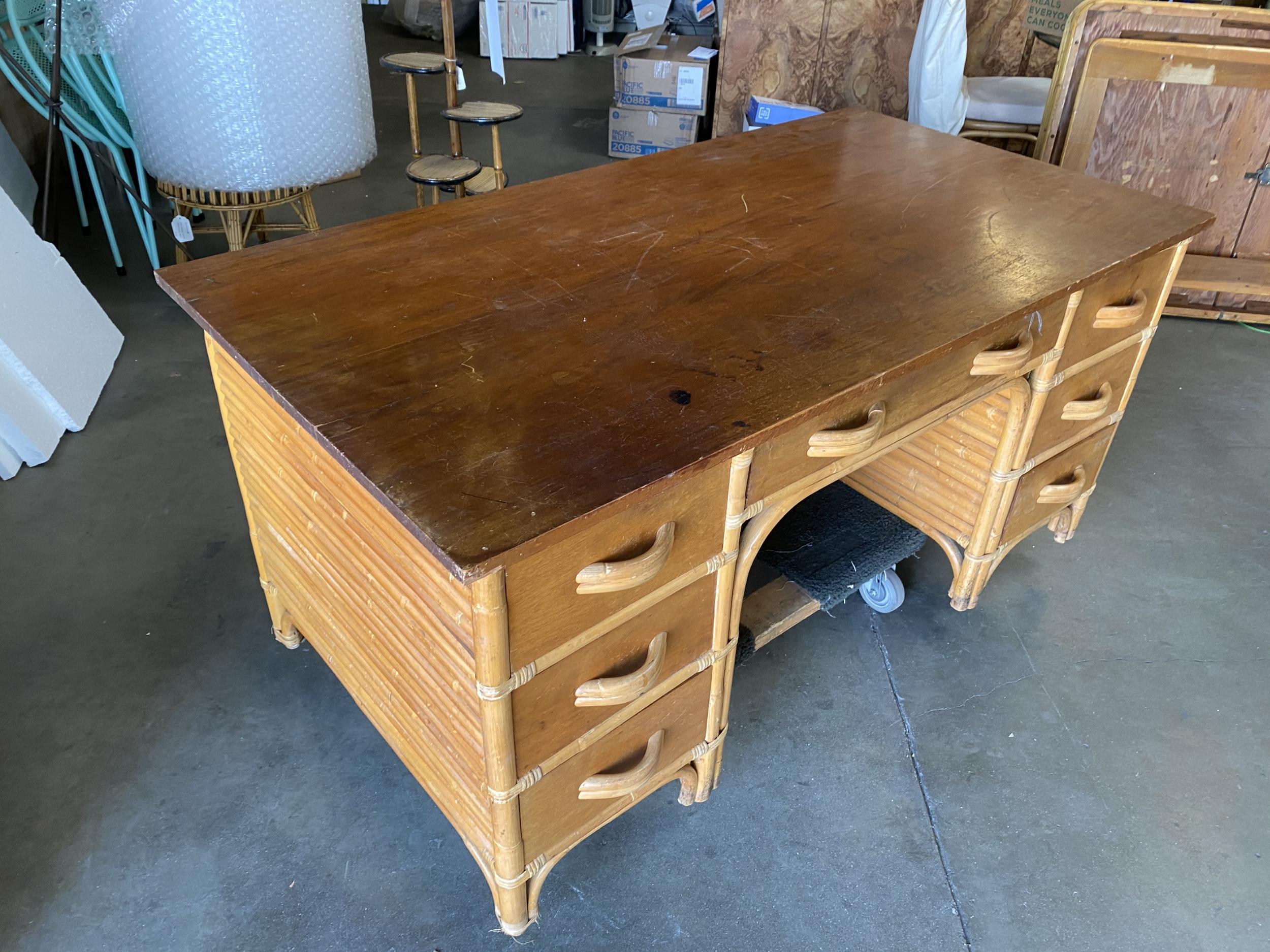 Restored very large stacked rattan desk, with Filipino mahogany. Drawer fronts, side panels, and top. The desk features a center drawer and six side drawers. Beautiful stacked rattan legs race from the top to the bottom, creating a great modern