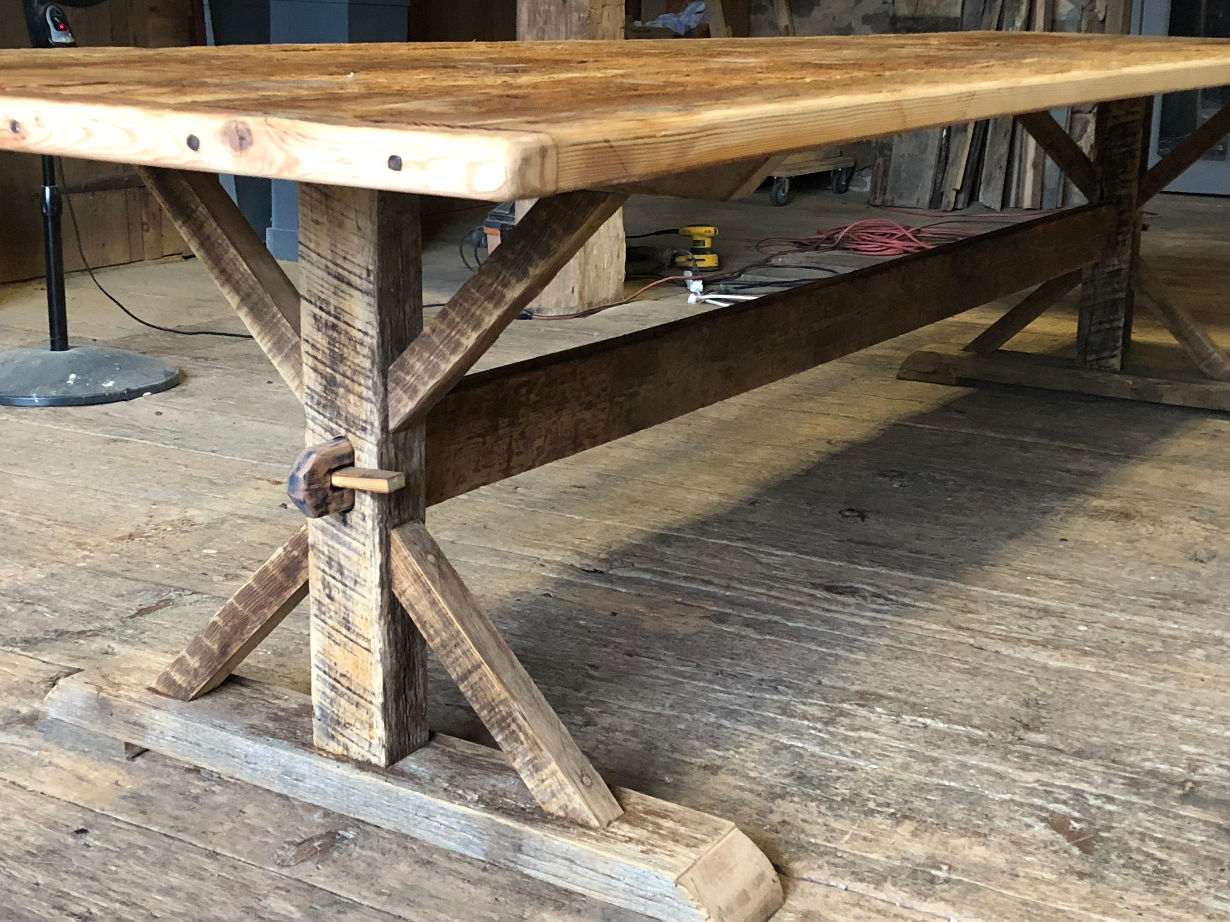 A large (almost 12 feet long) rustic pine and oak trestle table with a removable and reversible top with one side rough and rustic and the other side smooth and slightly whitewashed. The base disassembles by removing two wedges holding the stretcher
