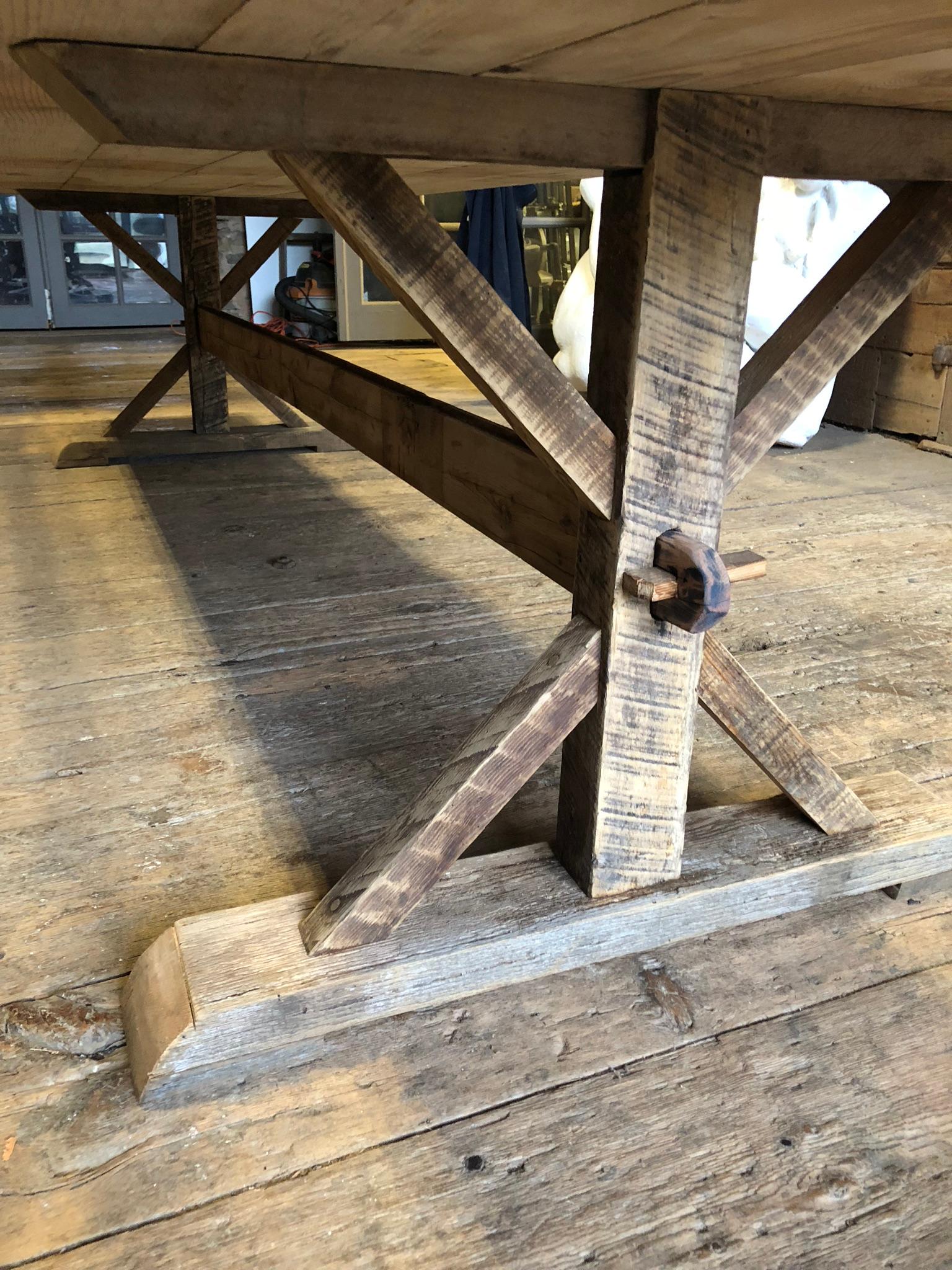 A large (almost 12 feet long) rustic pine and oak trestle table with a removable and reversible top with one side rough and rustic and the other side smooth and slightly whitewashed. The base disassembles by removing two wedges holding the stretcher