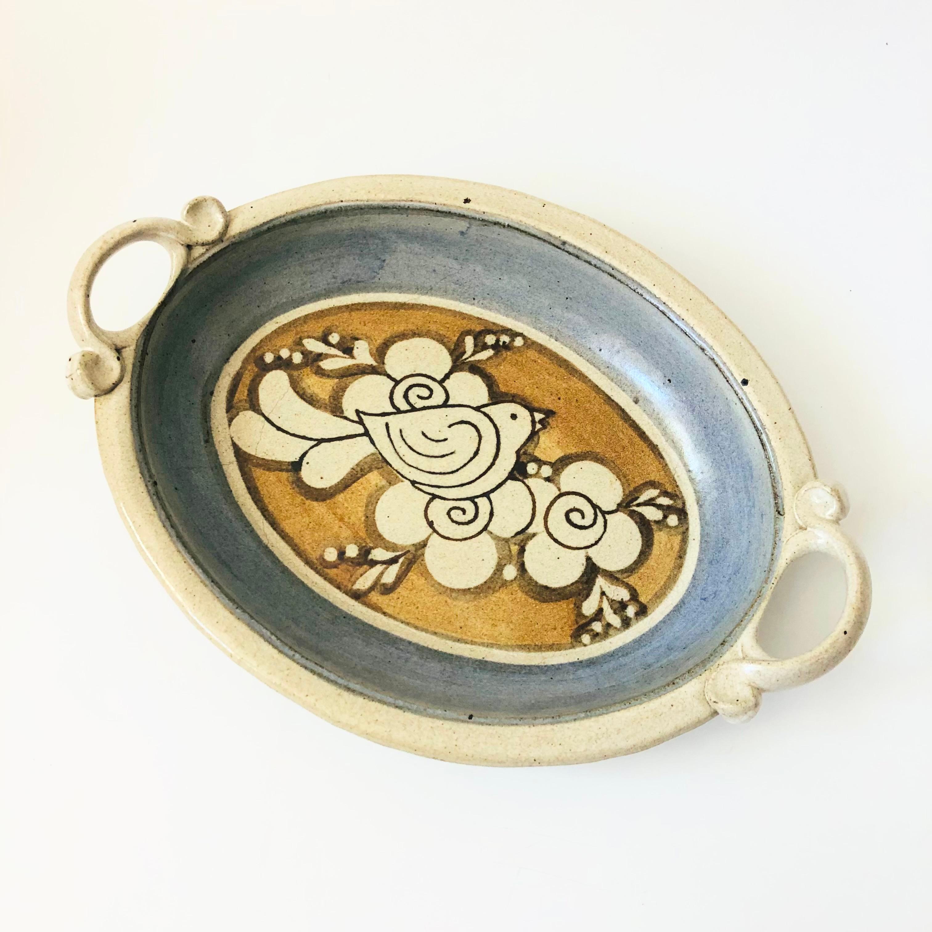 A vintage Rutherford studio pottery tray. Features a beautiful hand painted bird design in the center with handles formed on each side. Nice large oval size for serving or display. Signed on the base.


