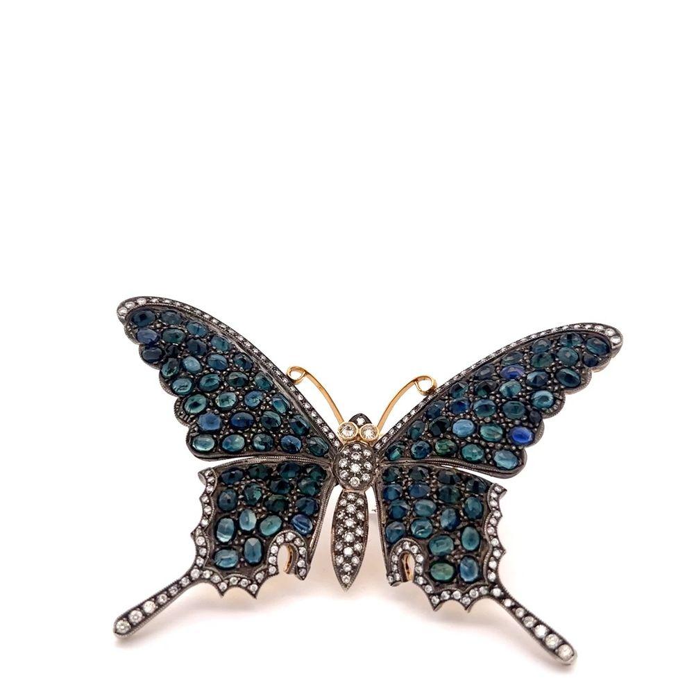 This exquisite butterfly pin features 18k yellow gold and silver, adorned with a captivating arrangement of sapphires and diamonds. The pin is meticulously crafted with attention to detail, resulting in a visually striking piece of jewelry. The