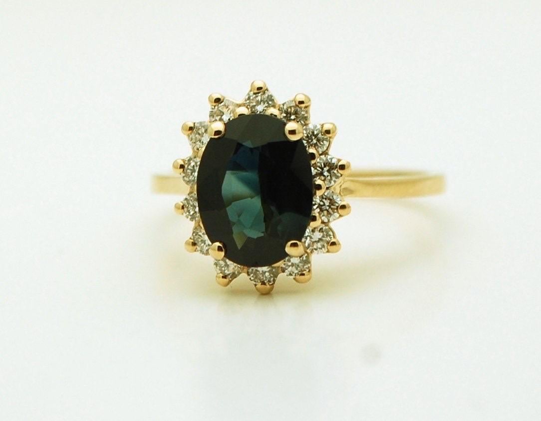 Splendido zaffiro ovale, di colore blu e di purezza leggermente inclusa, realizzato in un anello vintage a forma di aureola in oro giallo 18KT. L'anello è molto luminoso e scintillante! Lo zaffiro ha un peso di circa 2 carati, mentre i diamanti