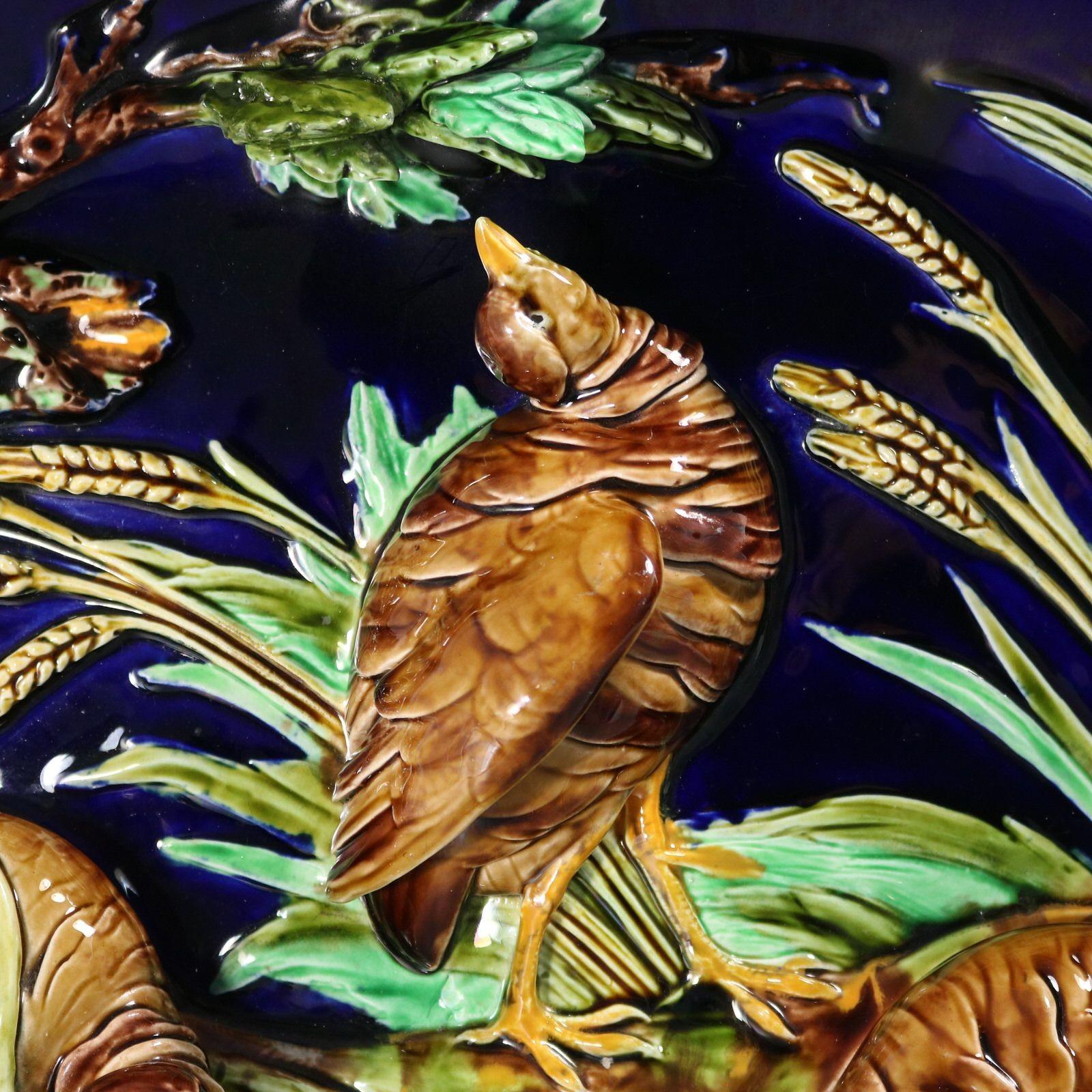 Sarreguemines Majolica wall plaque which features a scene of three partridges foraging for food, amongst wheat, oak and a pond. Molded in deep relief. Colouration: cobalt blue, green, brown, are predominant. The piece bears maker's marks for the