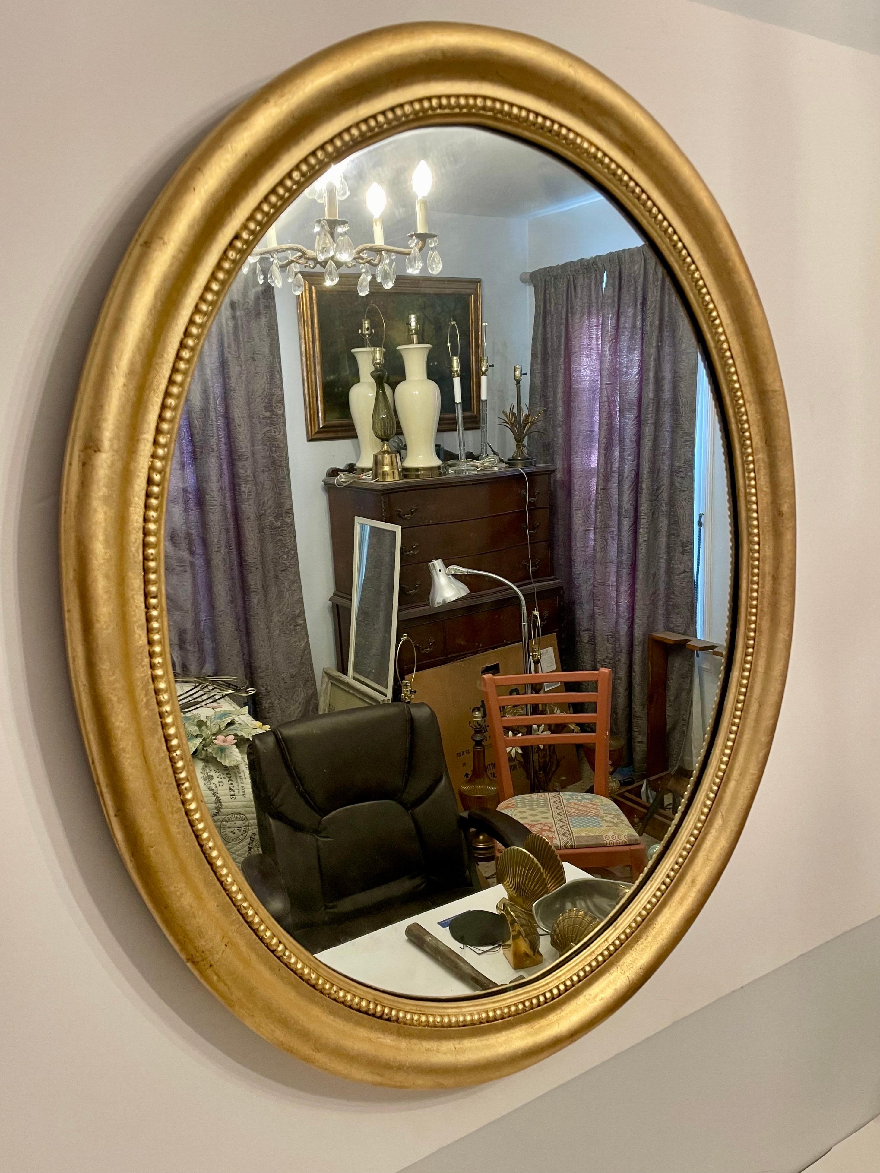 Large Scale 1940's Gilt Oval Mirror With Carved Beaded Surround Detail. Good overall condition, few rubs to finish from age and use as shown in photos. Mirror glass is stamped 1947, High Point North Carolina.  Wood back is marked 1948. Davis Cabinet