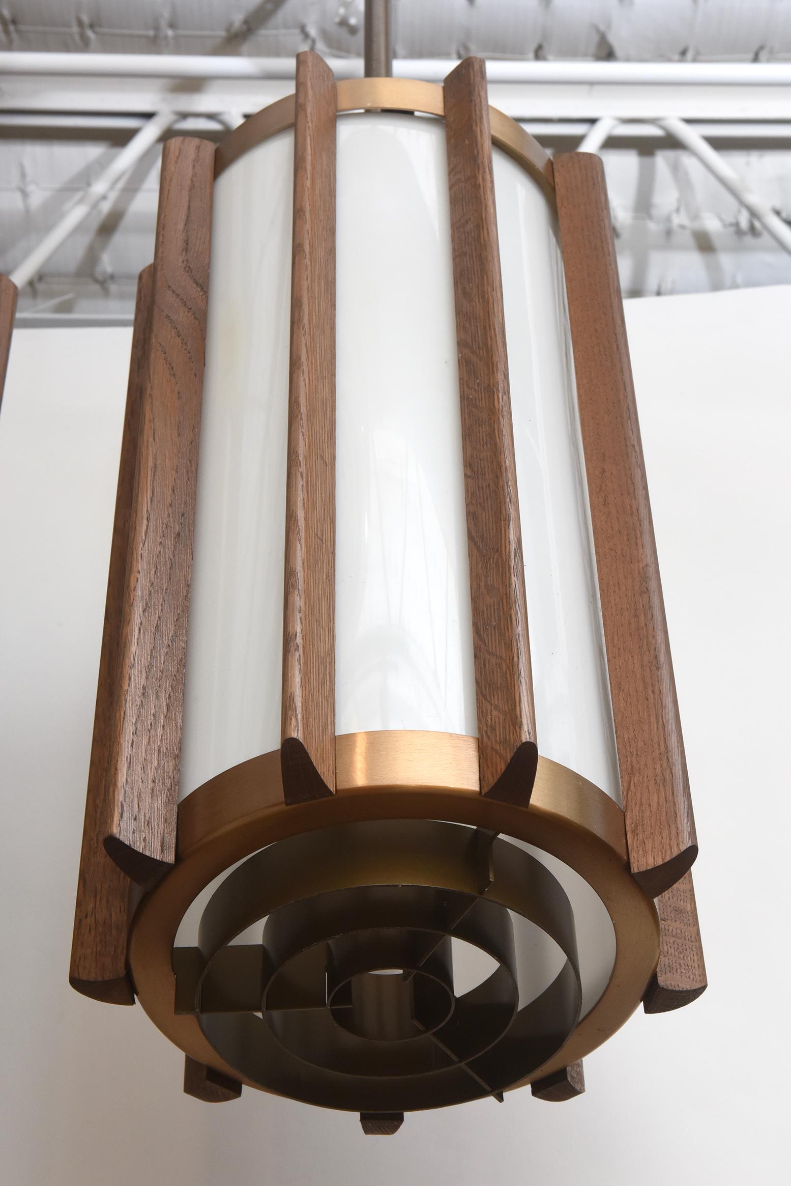 A masterful mix of materials and scale combine to make these Mid-Century Modern pendants in warm walnut, brass, and acrylic the perfect fixture in so many different environments. Originally from a church or commercial building, the pendants could