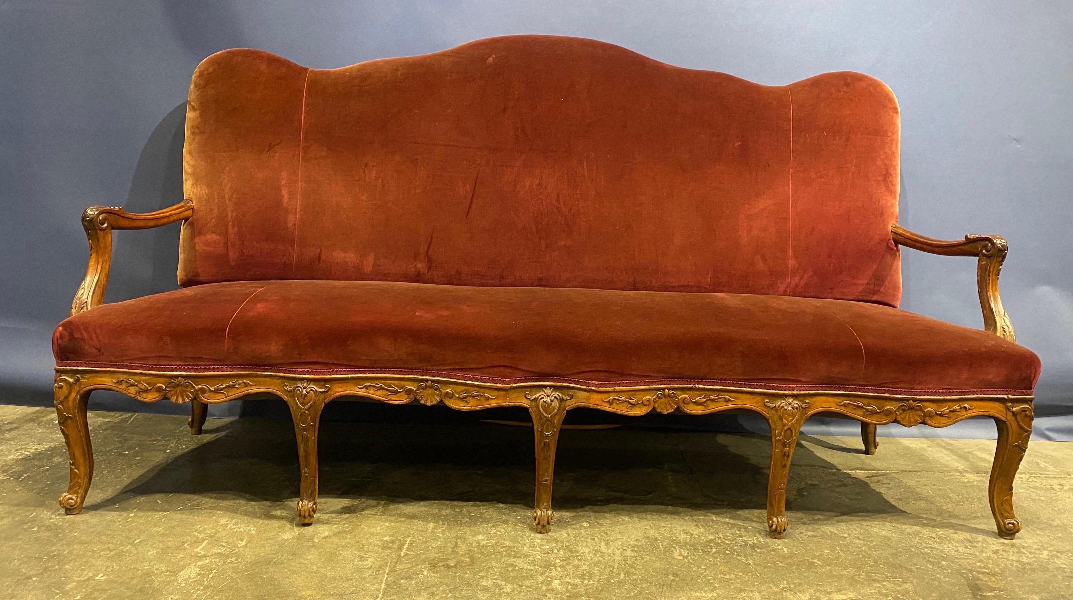 Large scale 19th century French carved walnut serpentine form sofa. Wonderfully carved apron and knees. Very comfortable. Velvet upholstery in pretty good shape, few minor spots. Could easily be reupholstered.
