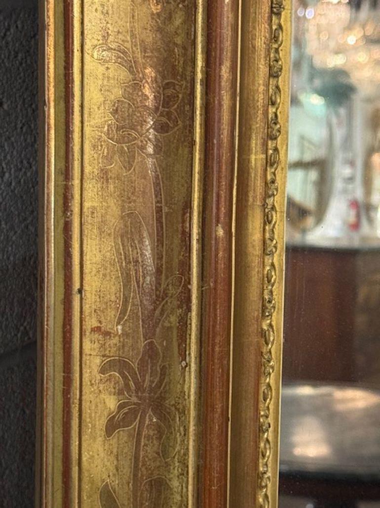 This large scale 19th century French Directoire gold gilt mirror exudes elegance and sophistication with its lovely classic design. This mirror adds a touch of luxury to any home décor setting. The intricate gold gilt framing, with a floral design