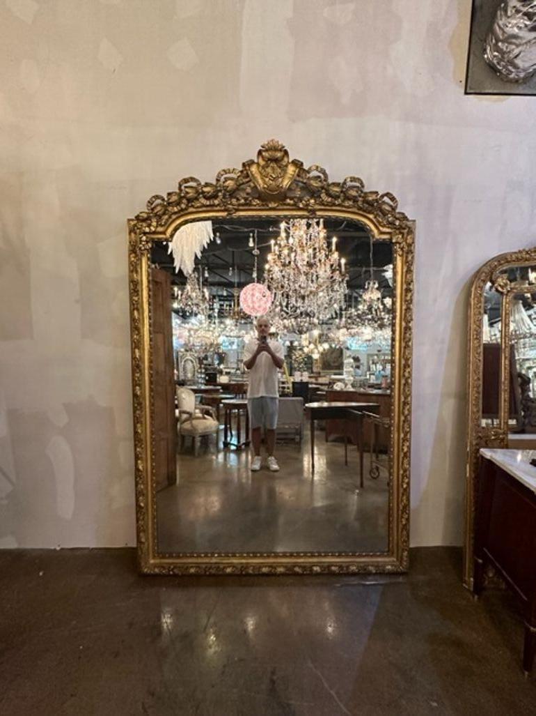 Spectacular large scale 19th century French Louis XVI carved and gold leaf floor mirror. Featuring floral images, ribbons and a gorgeous crest at the top. A true work of art!  Fabulous!!