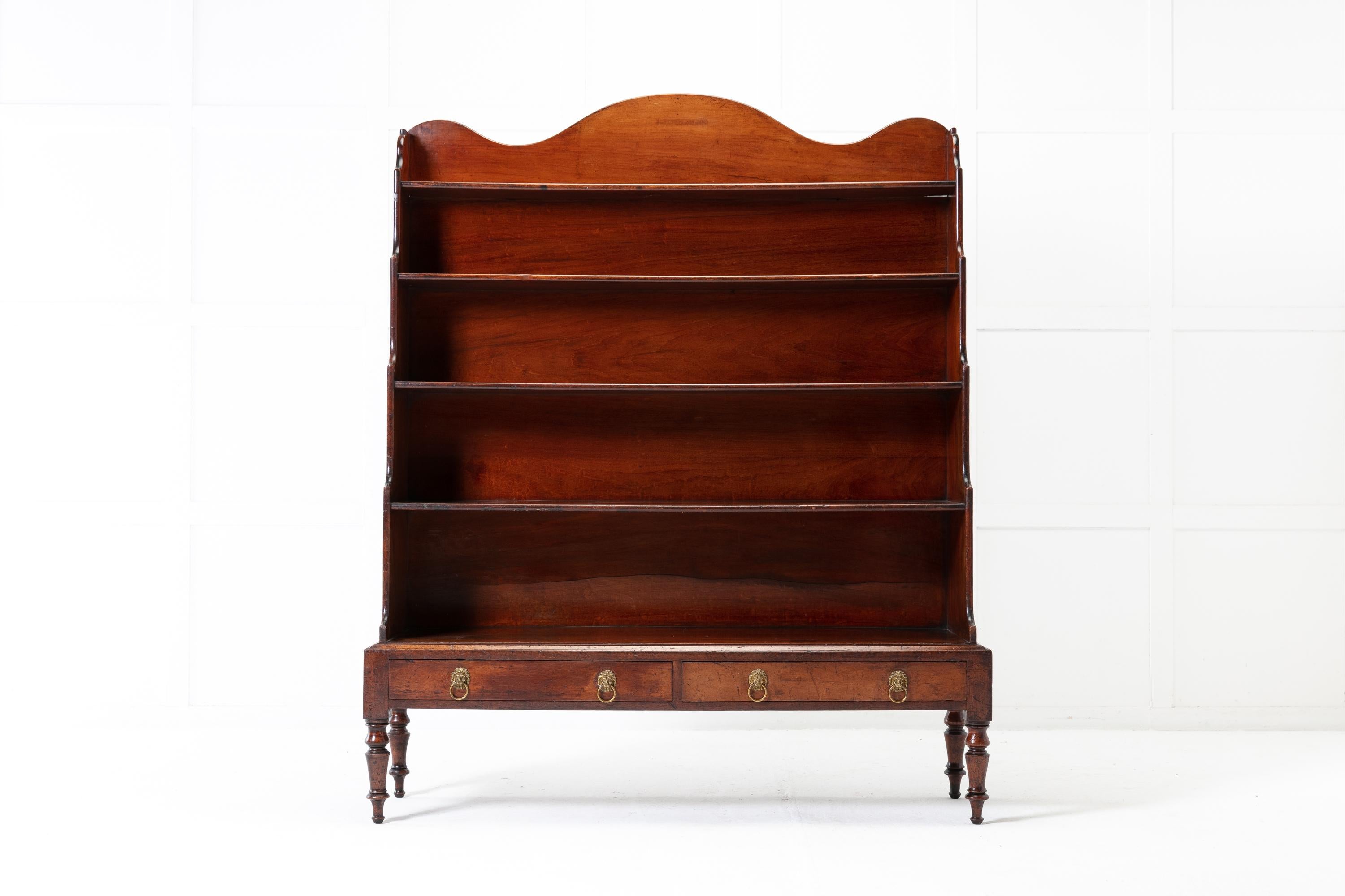 An unusual and large scaled 19th century mahogany waterfall/open bookcase of upright rectangular form with five fixed, graduated shelves. Having a shaped top over a panelled back. The waterfall sides having shaped tops. There are two lower drawers
