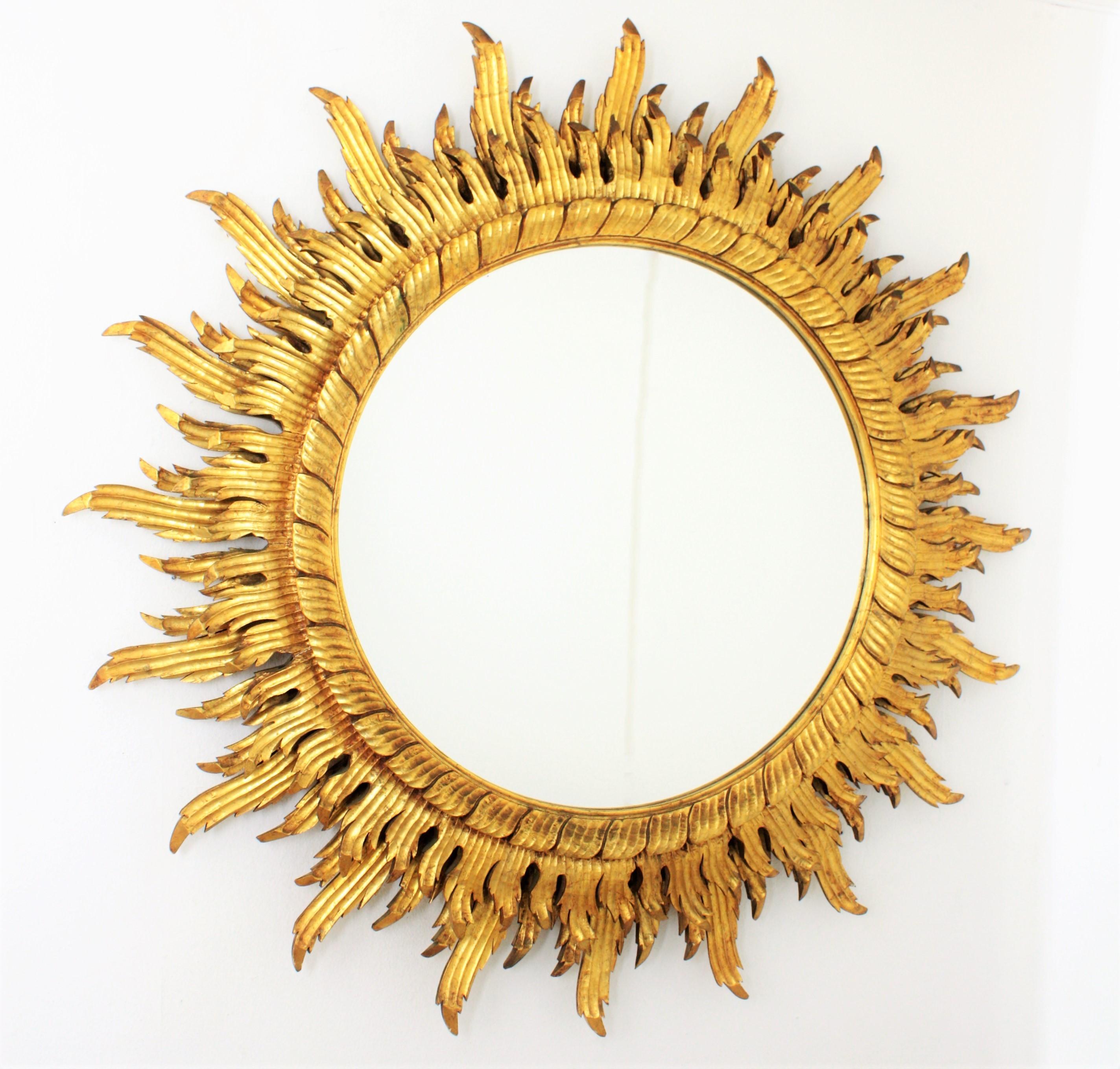 Unique large-scale (132cm diameter) Baroque style carved wood gold leaf gilt double layered sunburst mirror. Unusual piece in this size. The mirror has a wood carved round frame surrounding the circular glass and two layers of wood carved rays in