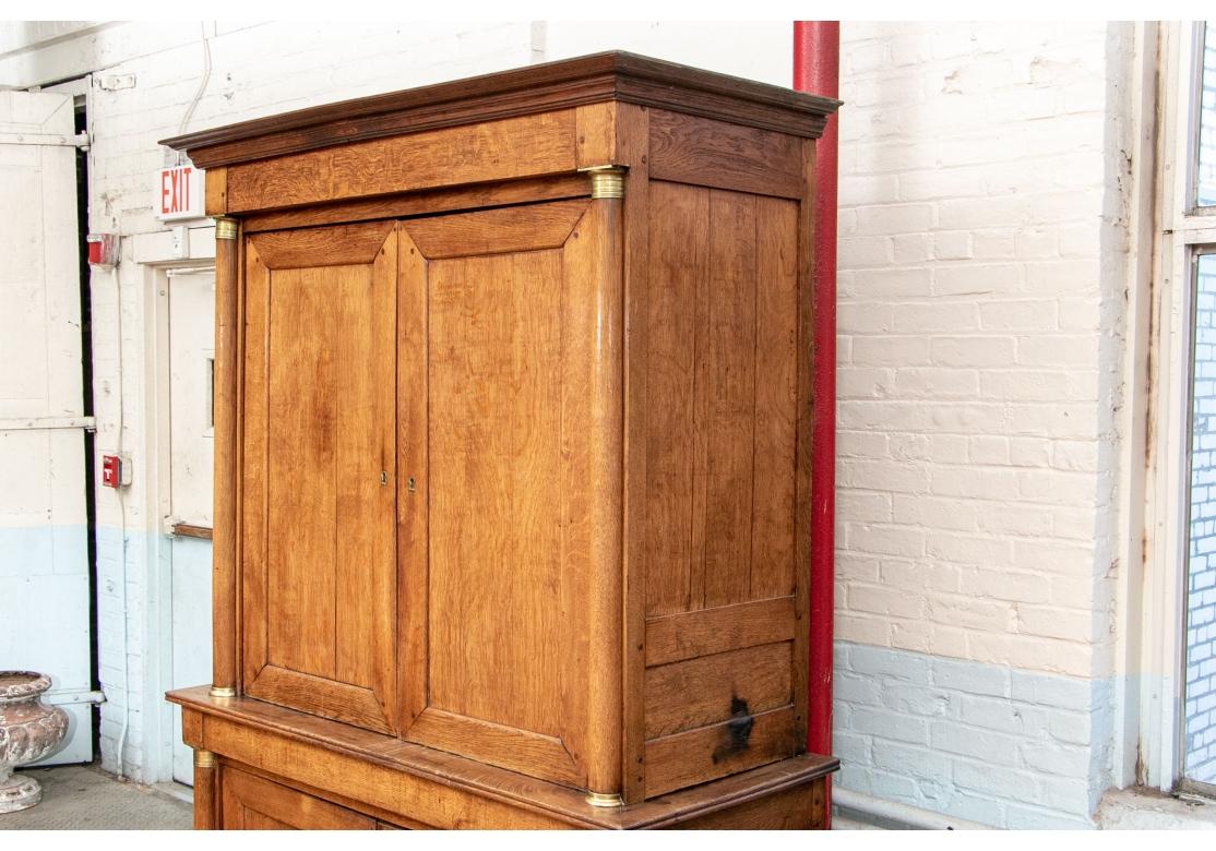 A large and fine Cabinet in the Louis Philippe Style. With a carved cornice over double recessed doors and half column supports with decorative brass capitals and bases. The interior with two interior shelves and two frieze drawers. Lower double