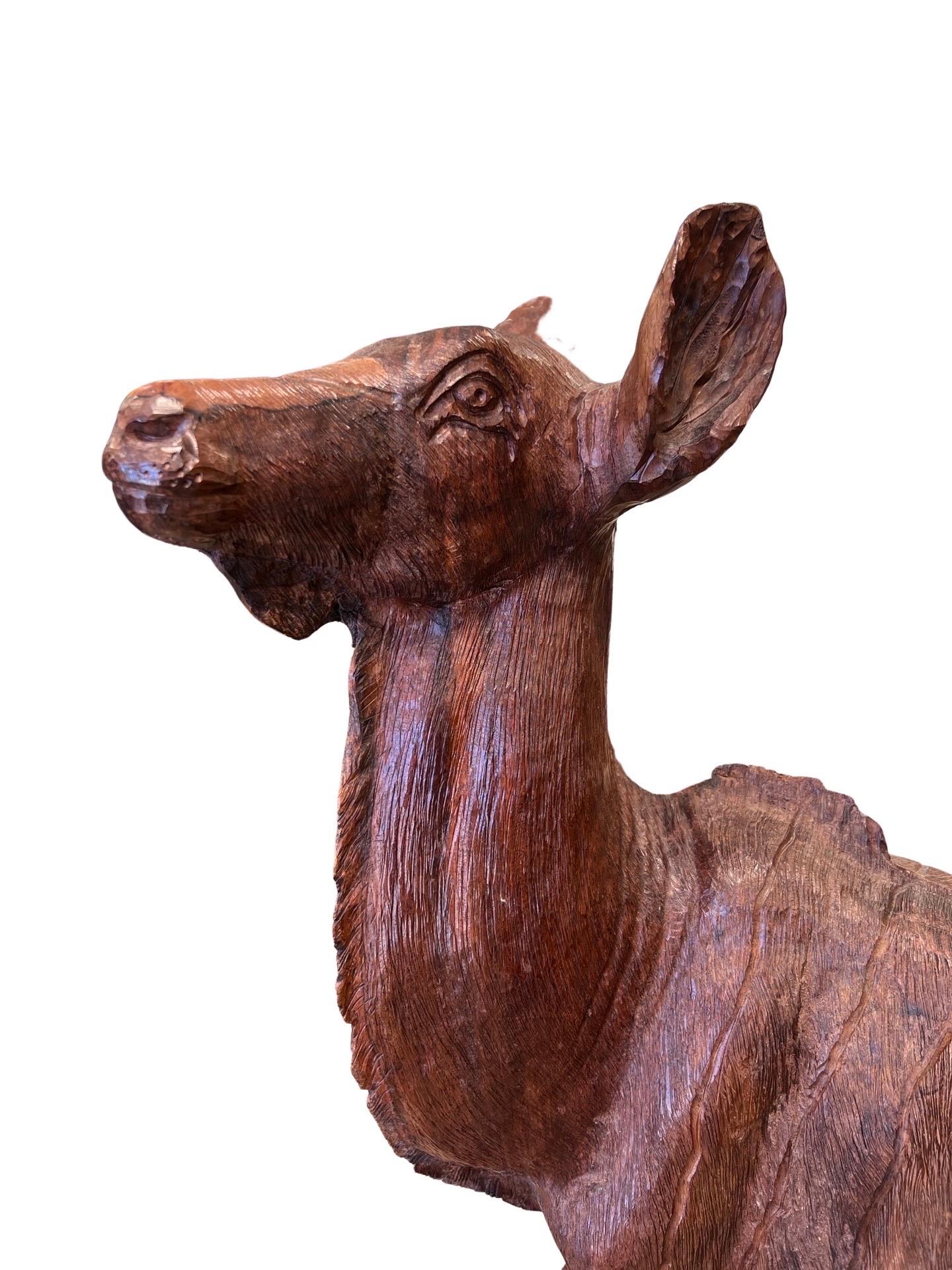 A large and heavy Black Forest style carving of a deer. Taken from a single piece of wood, the base carved to resemble a mountain side while the body itself is carved in a female deer form. Unmarked.