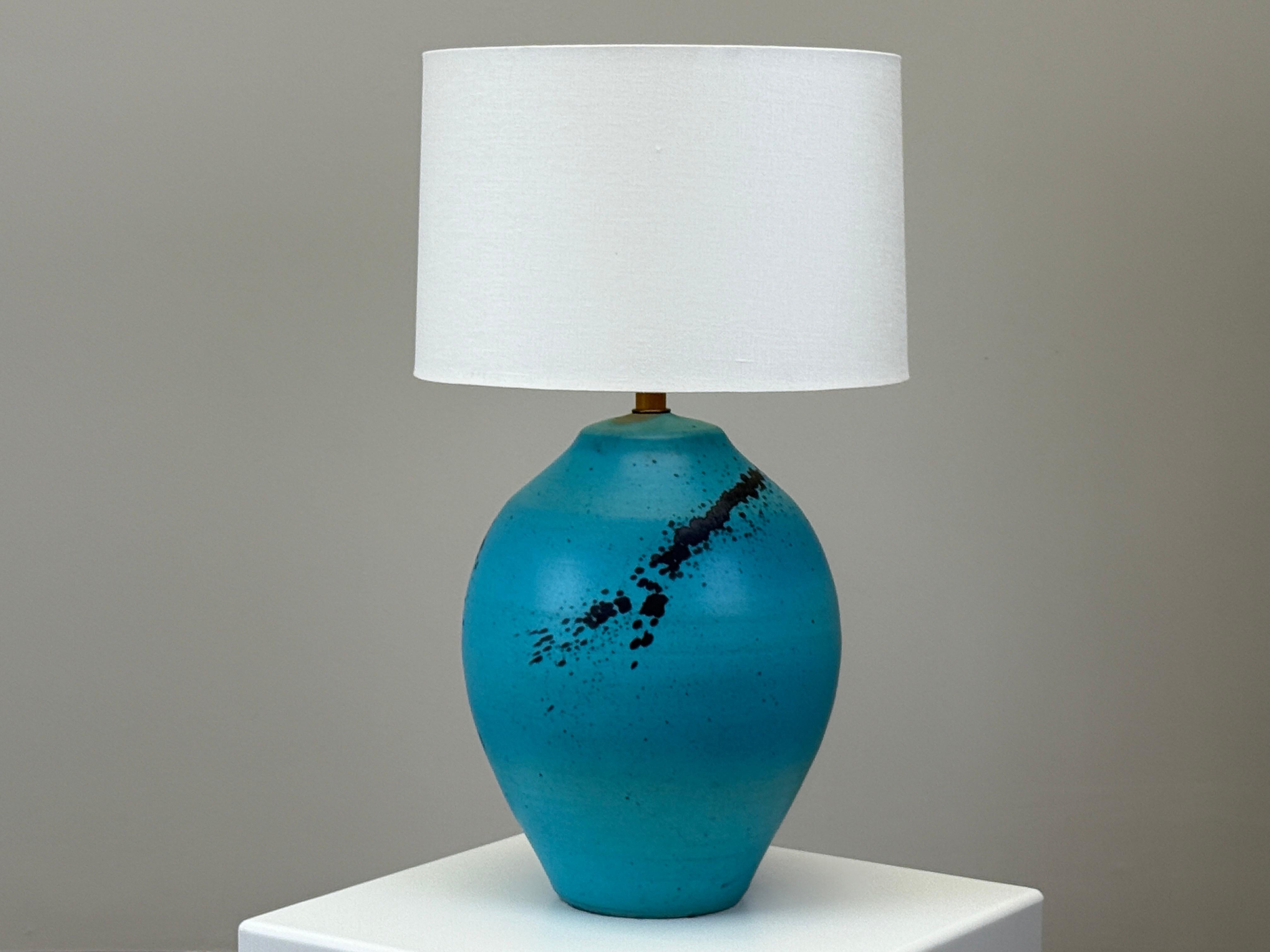 A large scale ceramic table lamp with bright blue gaze. 