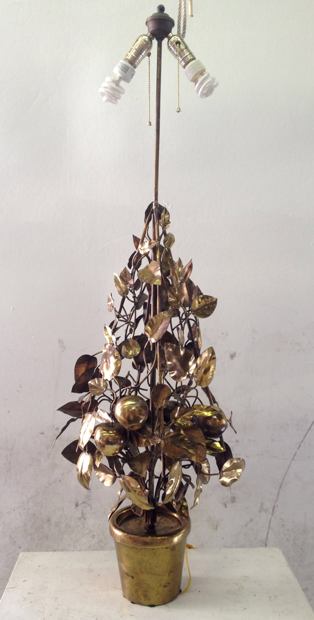 The central form of this large brass lamp is a tapered tree with apples. Each branch, leaf, and apple are constructed in brass and are supported by a brass frame. The lamp has two bulbs which can be illuminated independently of one another.