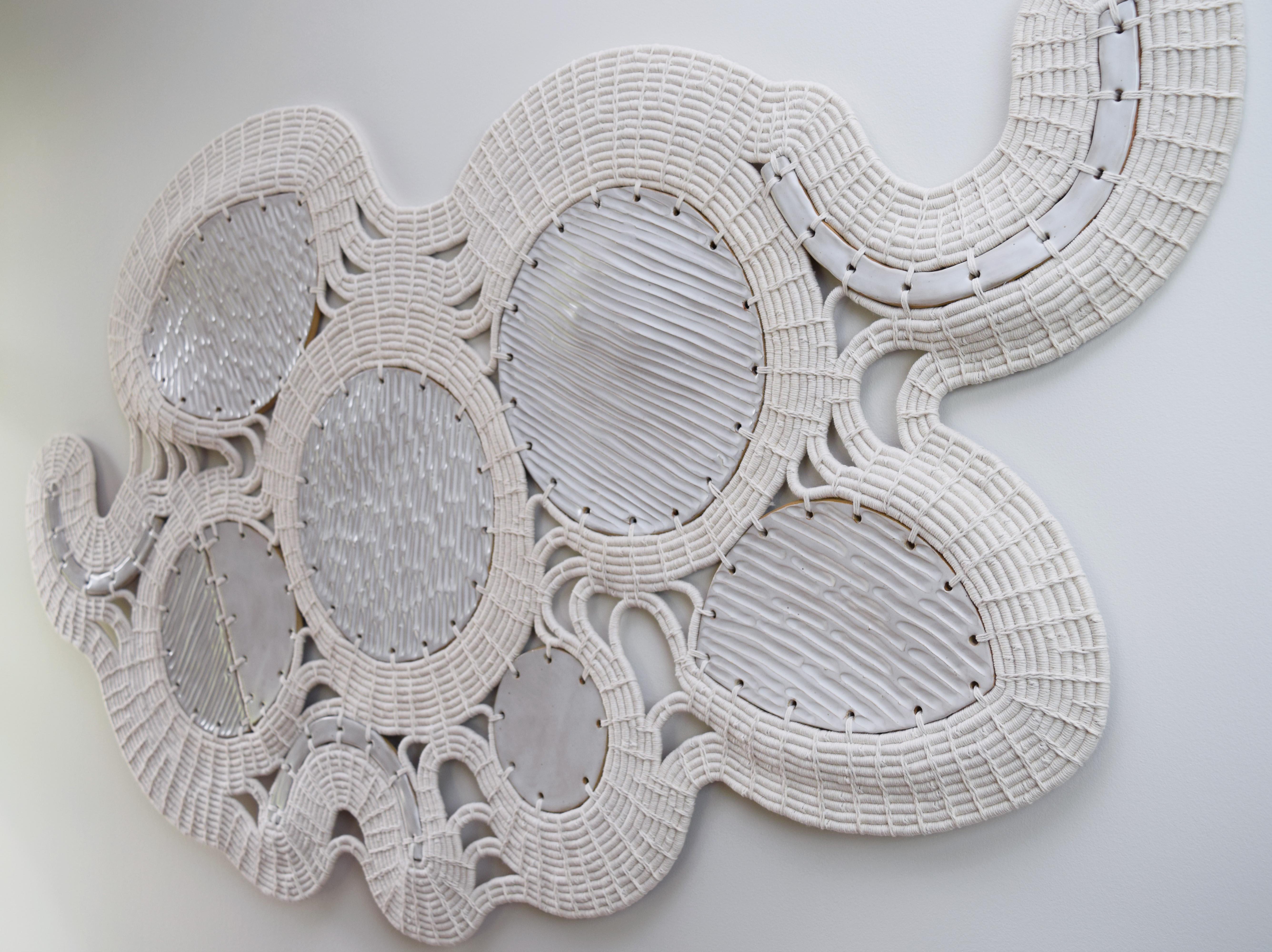 Wall sculpture #789 by Karen Gayle Tinney

One of a Kind Wall Sculpture in ceramic and cotton. Handmade ceramic shapes are finished with satin white glaze. The ceramic pieces are linked together using a coiling technique in white cotton. Wires for
