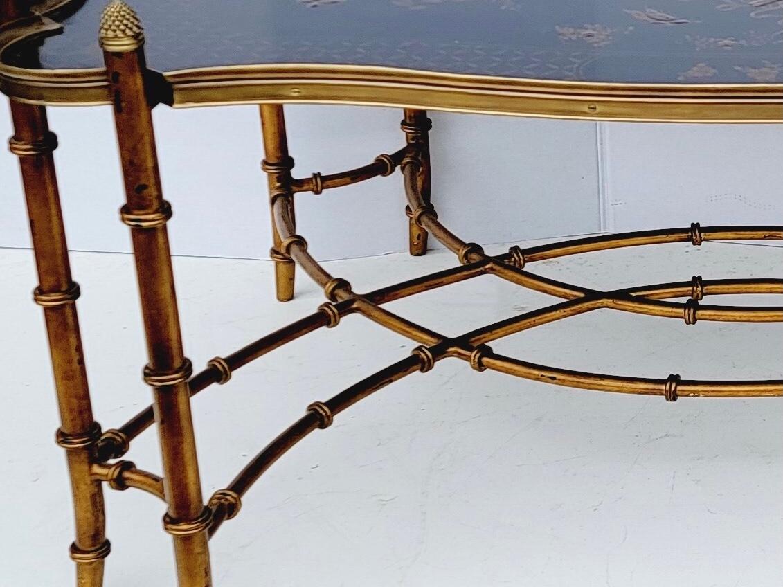 This is a very good looking large scale Chineses Chippendale style faux bamboo coffee table. The tray is not removable. The supports are wood and brass with pineapple finials. The tray portion is black lacquer with chinoiserie details. It is