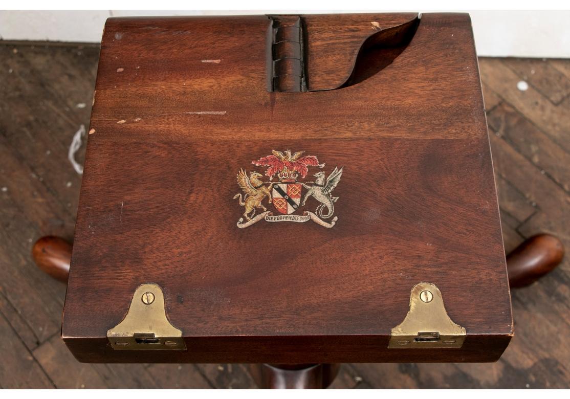 With a fine book matched figured wood top separate from the tripod base with a painted crest with griffins in the manner of Theodore Alexander. The crest with Dieu et mon droit which means 'God and my right' is the motto of the monarch of the United